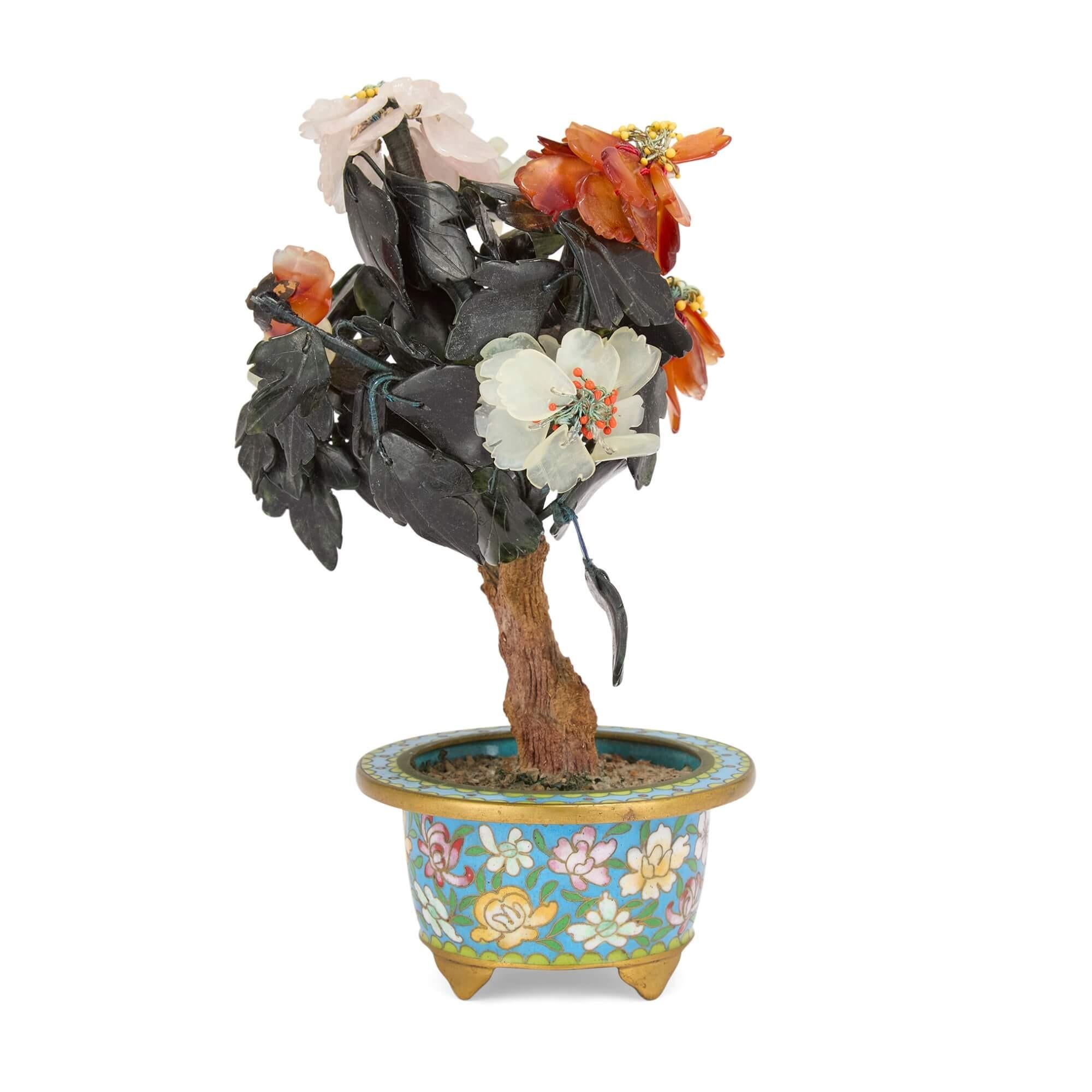 Modello di fiore cinese in pietra dura in un vaso di fiori in smalto cloisonné
Cinese, XX secolo
Altezza 18cm, larghezza 11cm, profondità 11cm

Questo intricato modello di fiore combina una super smaltatura cloisonné con diverse pietre semi-preziose