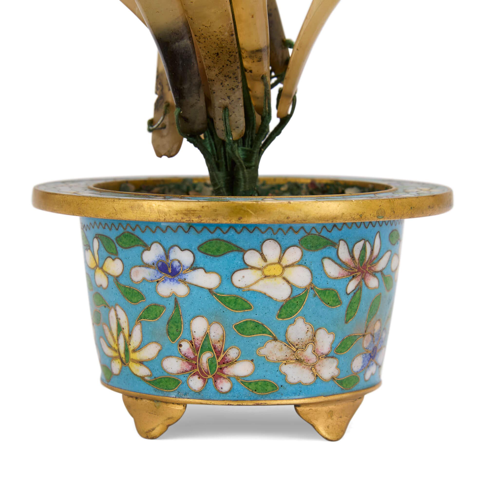 Modèle de fleur en pierre dure chinoise dans un cache-pot en émail cloisonné
Chinois, 20e siècle
Hauteur 20cm, largeur 12cm, profondeur 9cm

Ce superbe modèle de fleur réunit une multitude de pierres précieuses, placées à l'intérieur d'un cache-pot