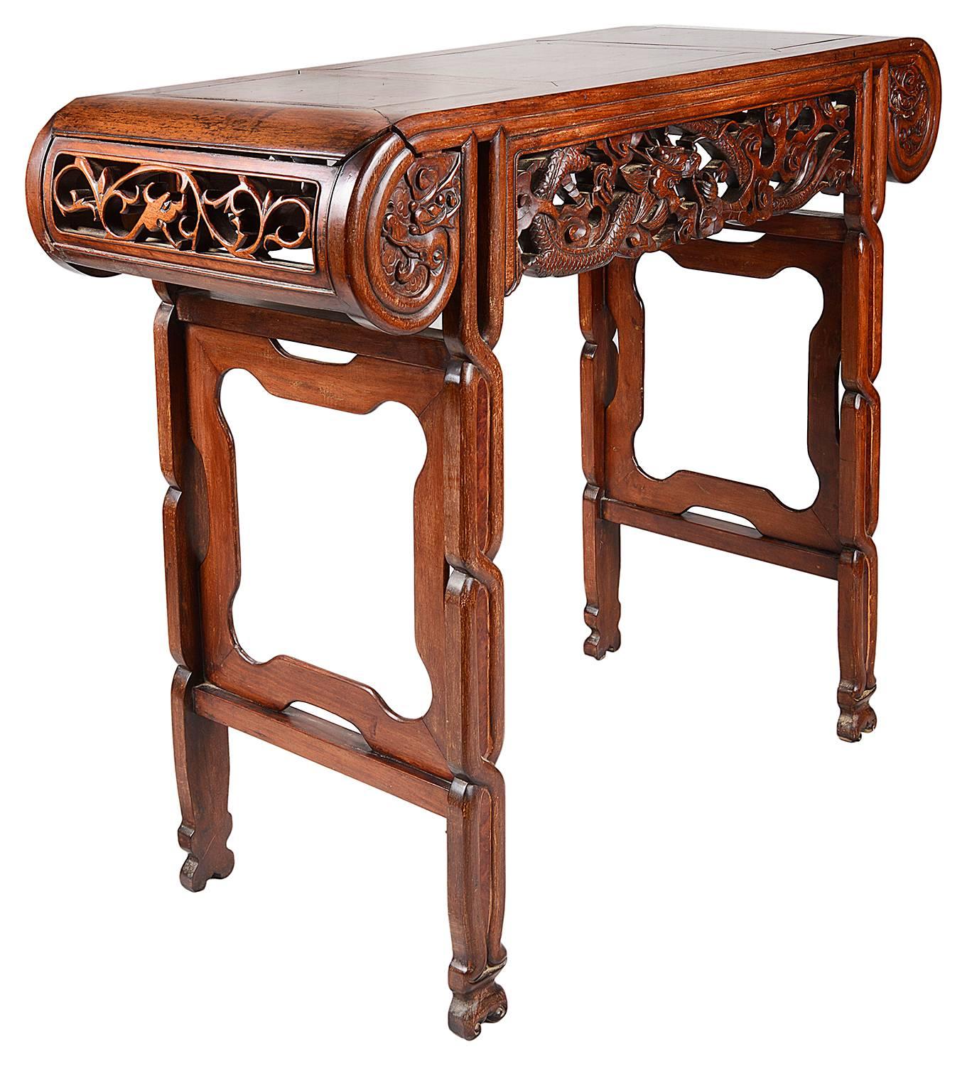 A good quality 19th century Chinese hardwood alter table, having a three panelled burr wood top. Carved scrolling ends with foliate decoration, the frieze with carved mythical dragons entwined. Raised in end supports with stretchers between and
