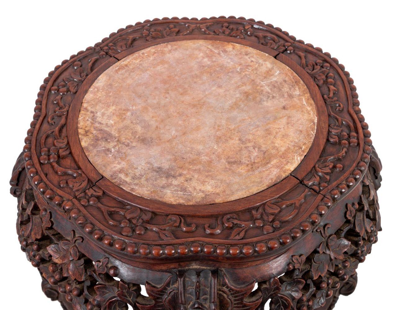 Chinese Carved Hardwood and Marble Pedestal Table, late 19th century, profusely carved, the lobed top inset with marble, on tall scrolled legs joined by an undertier. 37