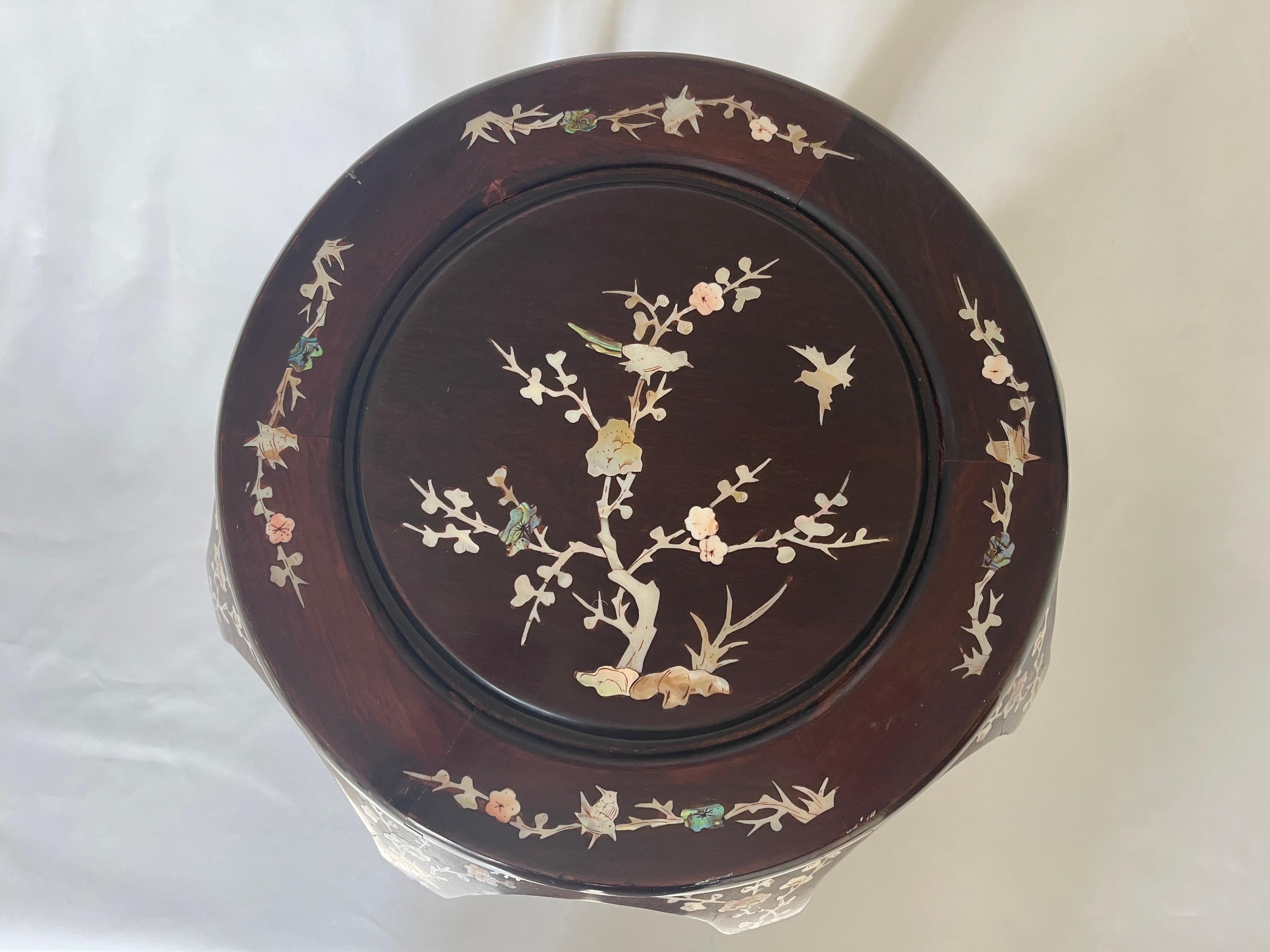 Chinese curved melon shape hardwood garden stool or side table with mother of pearl inlay.
Beautiful floral tree and bird motif inlaid top, with floral sprays at top of curved wood base.