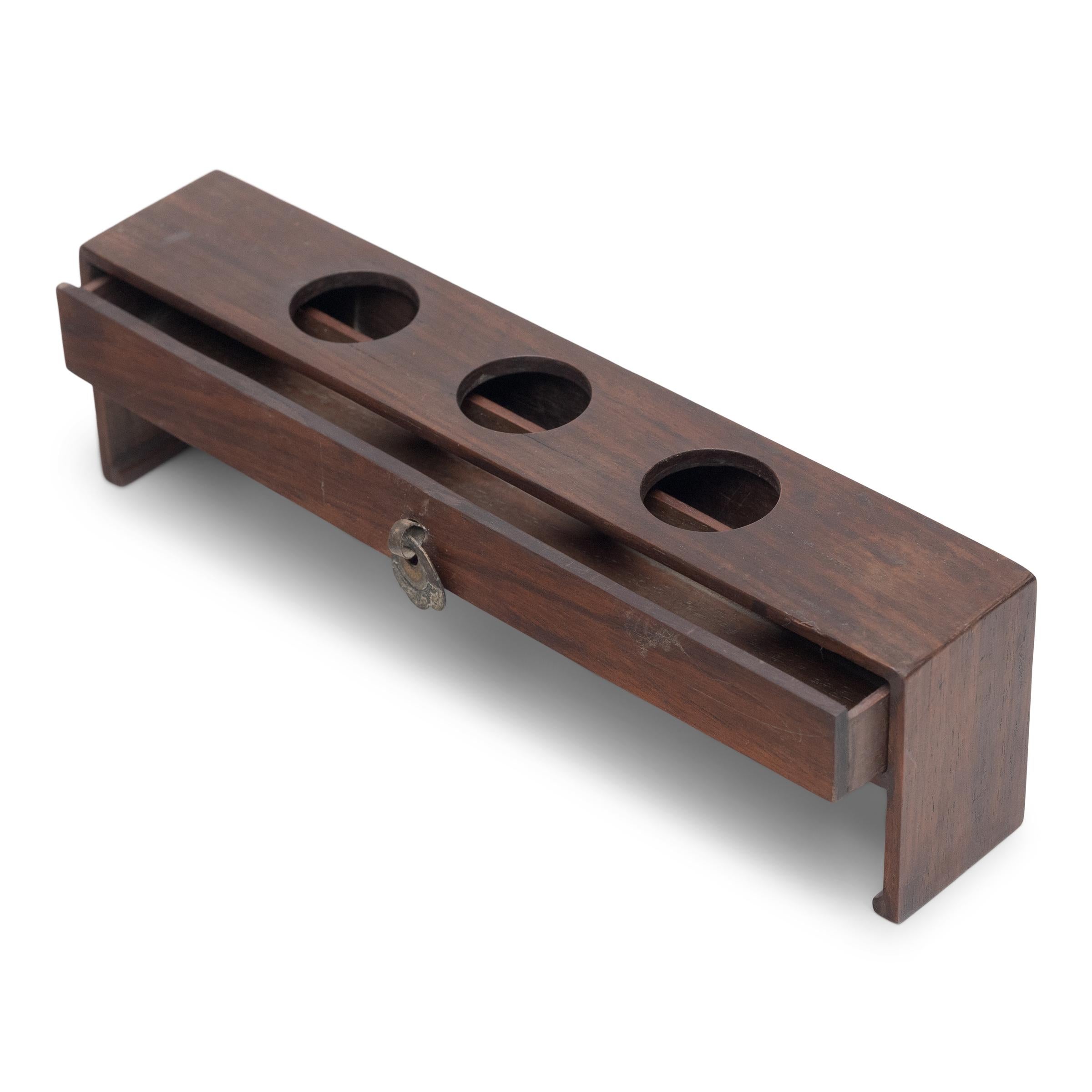 Designed to resemble a scroll-form altar table, this narrow footed box has an elegant silhouette with waterfall sides and minimal ornamentation. Dated to the late 19th century, the box is crafted of a dark hardwood and was once used to elevate an
