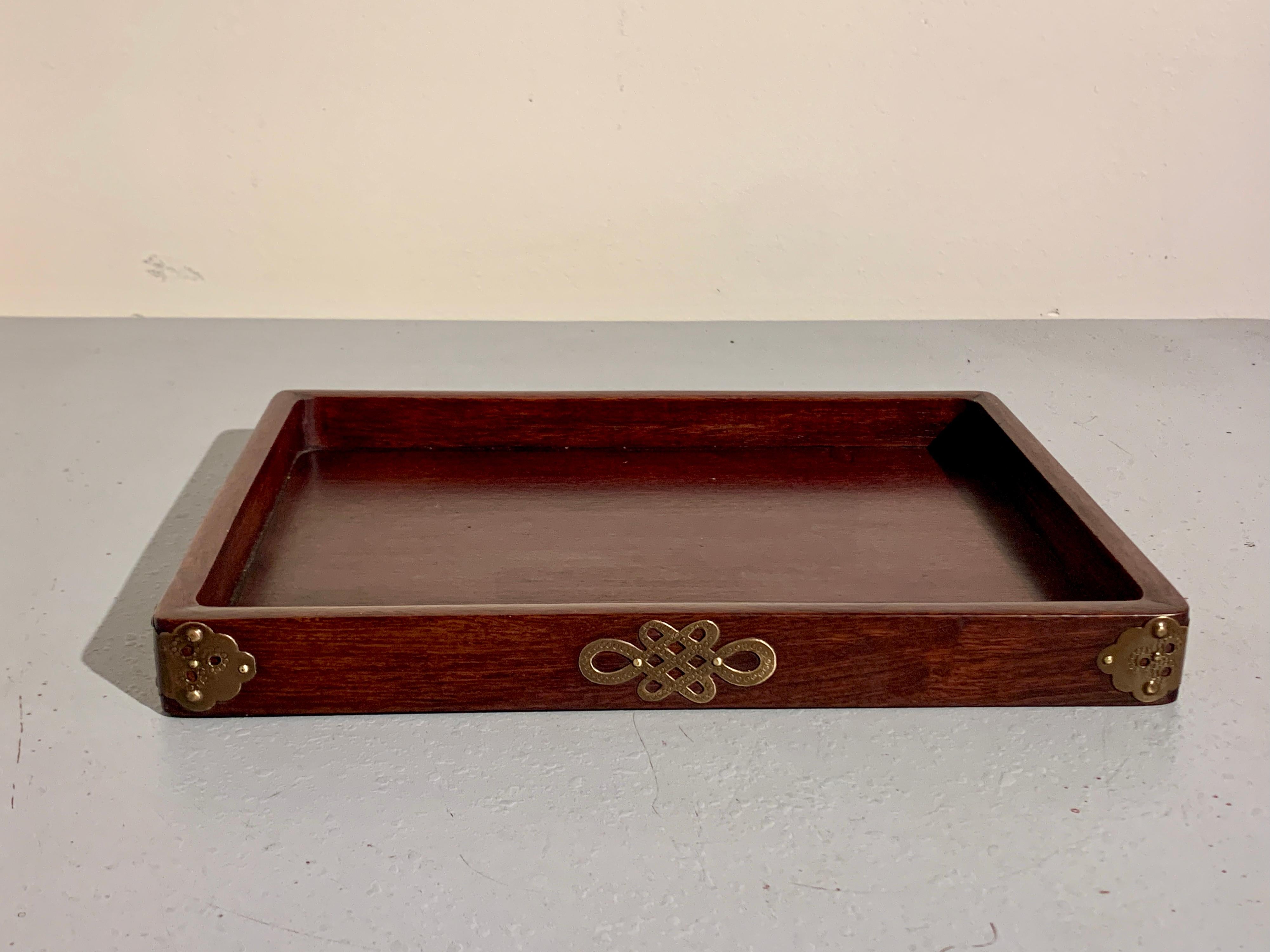 A simple and elegant Chinese hardwood and brass mounted scholar tray, late Qing Dynasty, circa 1900, China.

The scholar tray crafted of a solid and heavy densely figured hardwood of dark reddish brown color, and features an inset floating panel.