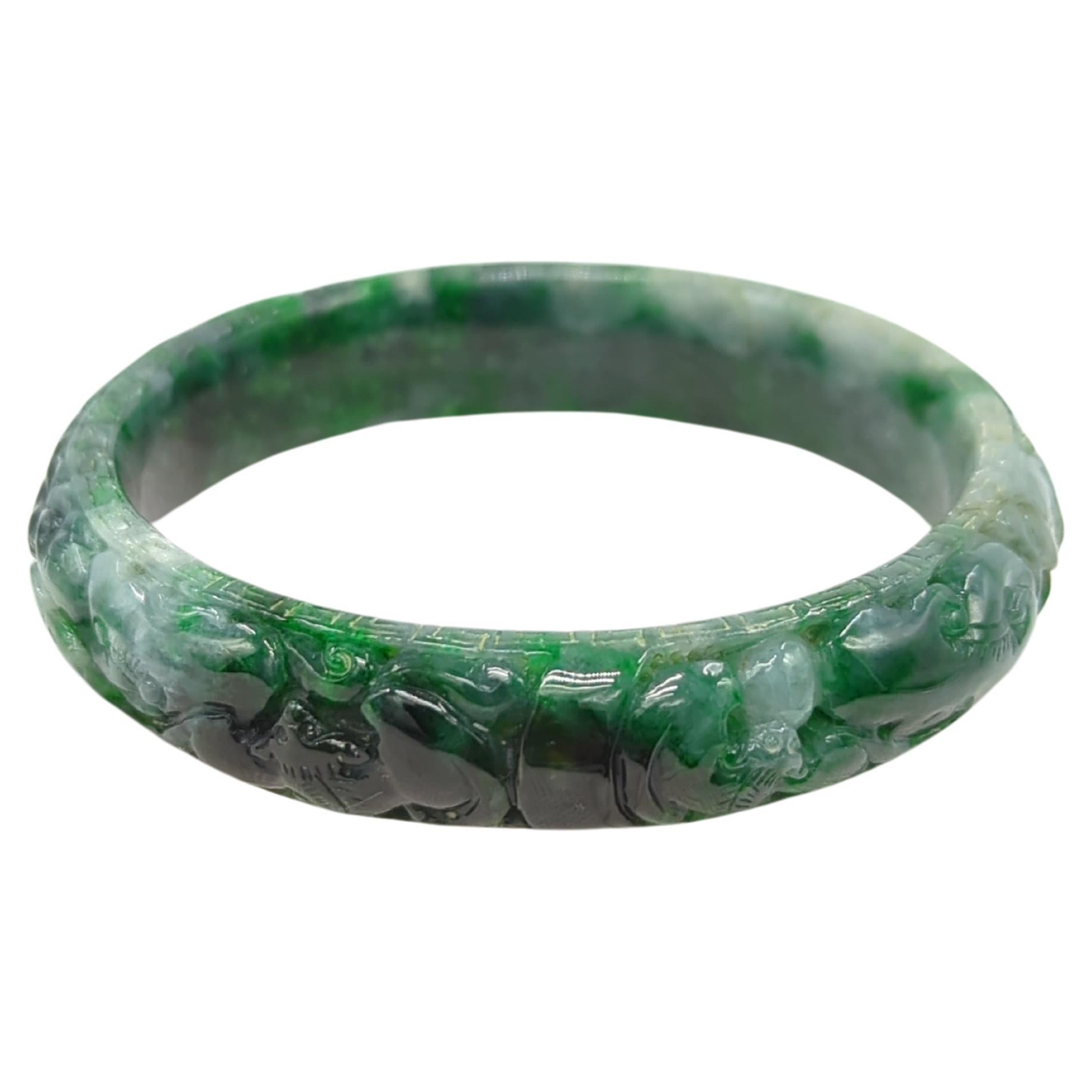 A vintage Chinese heavily carved natural jadeite bangle, displaying rich natural mottled colors including pale green, emerald to dark ink green.

ID: 60mm
OD: 76mm
Width: 14mm
Weight: 54.5grams
Grade: A-grade jadeite, no enhancements, completely