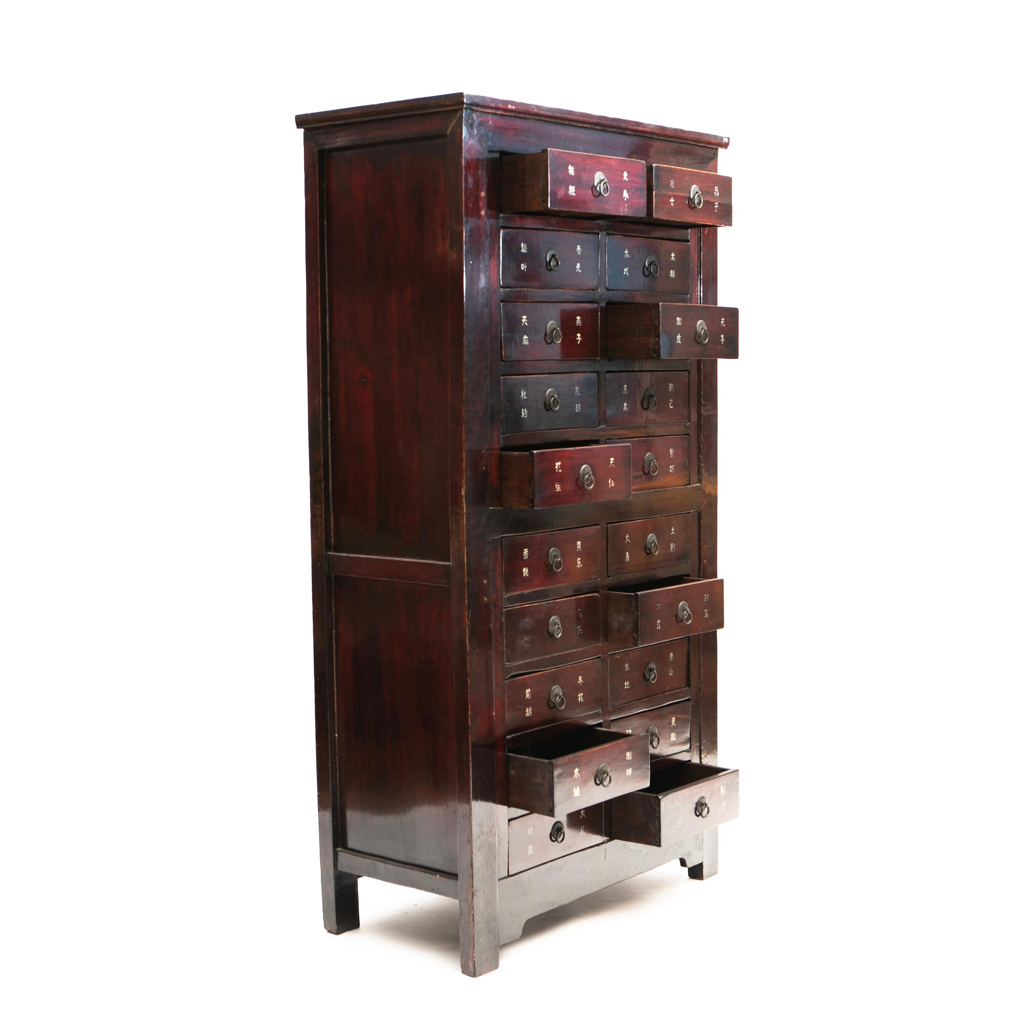 This elm wood apothecary cabinet, also known as a medicine chest, is an impressive piece of history with 20 unique drawers. The original burgundy lacquer has developed a beautiful natural patina over the years.
Each drawer is intricately detailed