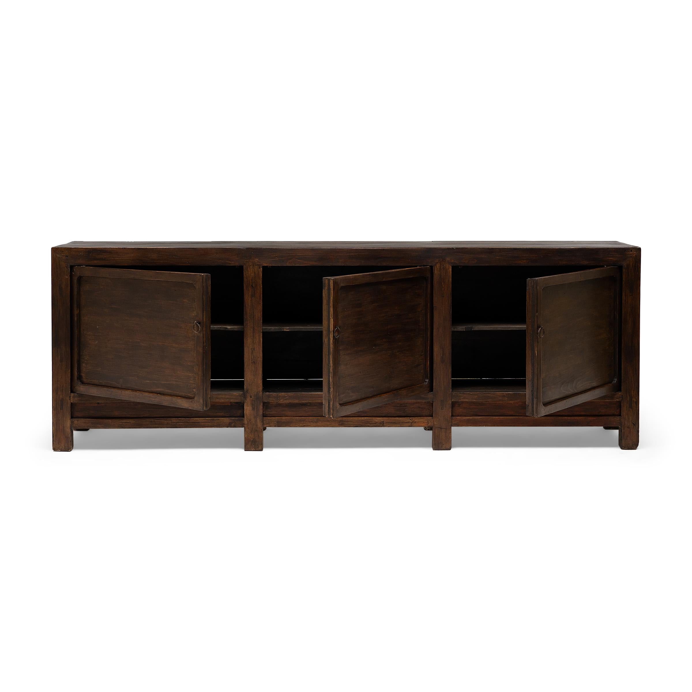 Created in the style of Mongolian storage coffers, this early 20th-century herdsman's chest has a clean lined design with charming rustic appeal. The square corner cabinet features three doors with metal loop handles that open to a large interior