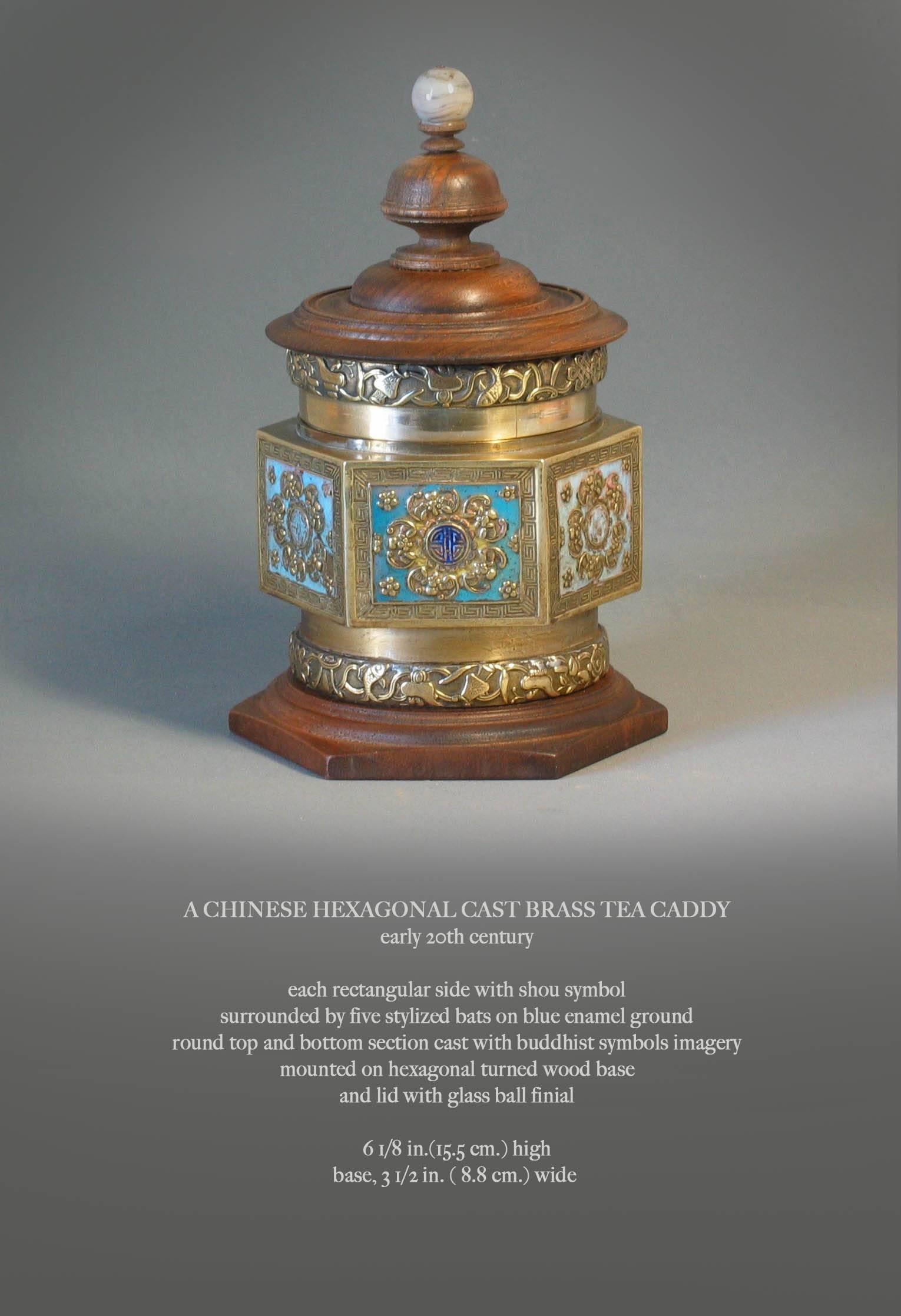 A Chinese hexagonal cast brass tea caddy, early 20th century. Each rectangular side with a shou symbol surrounded by five stylized bats on blue enamel background, round top and bottom section cast with Buddhist symbols imagery, mounted on hexagonal
