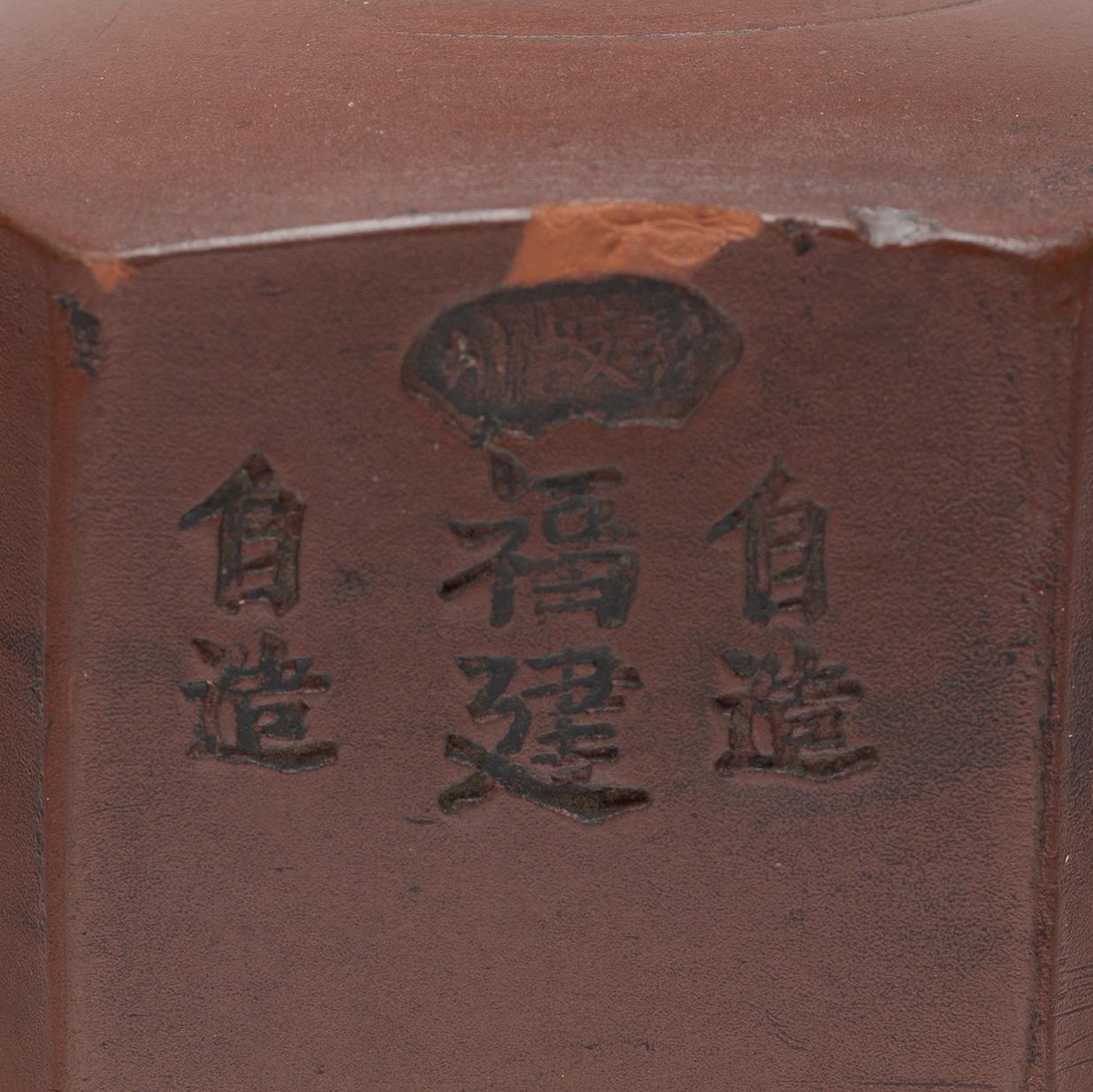 This unusual object is an early 20th century opium pipe bowl, sculpted of fine yixing red clay to a squat, six-sided form and fitted with a brass collar. Minimal and refined, the pipe bowl is decorated only by the maker's mark and text prominently