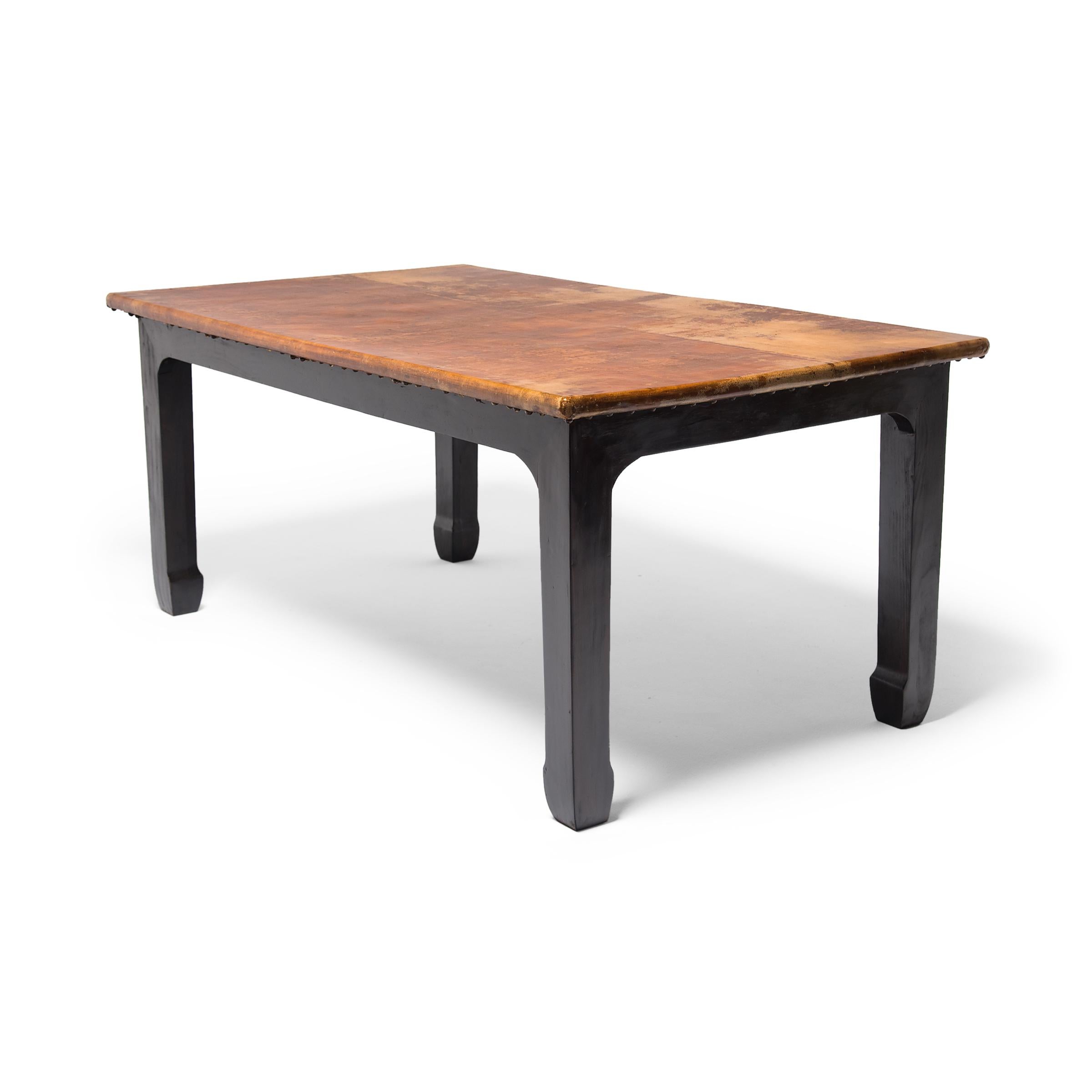 This artisan-made table from Canton, China rests on a darkened frame with hoofed feet, constructed of reclaimed northern elmwood (yumu). The expansive tabletop is covered in a select vintage mottled hide finished in lacquer and secured with a trim