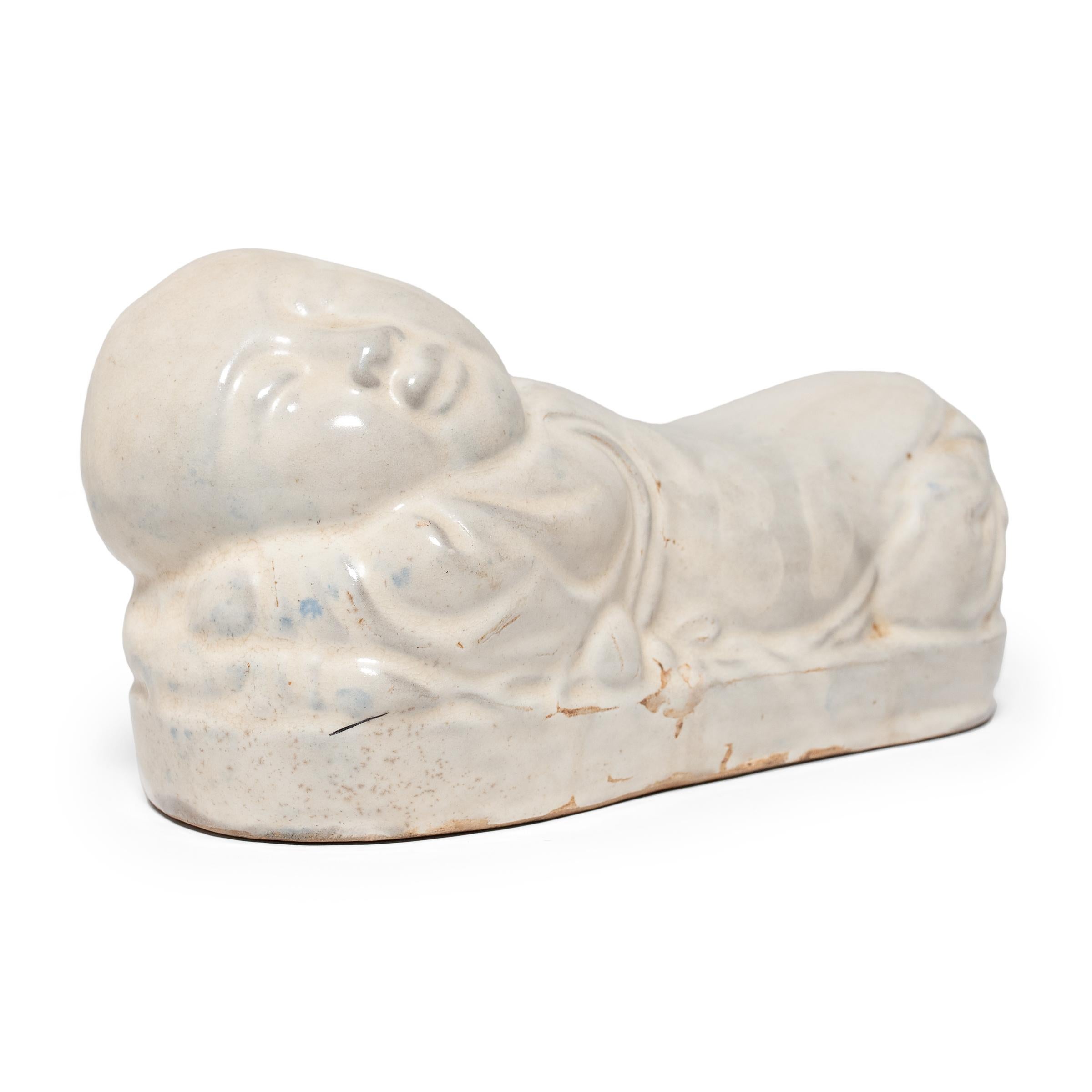 To keep her elaborate hairstyle intact while sleeping, a well-to-do Qing-dynasty woman once used this ceramic headrest as a pillow. This headrest is shaped in the form of a baby boy, a motif commonly termed 