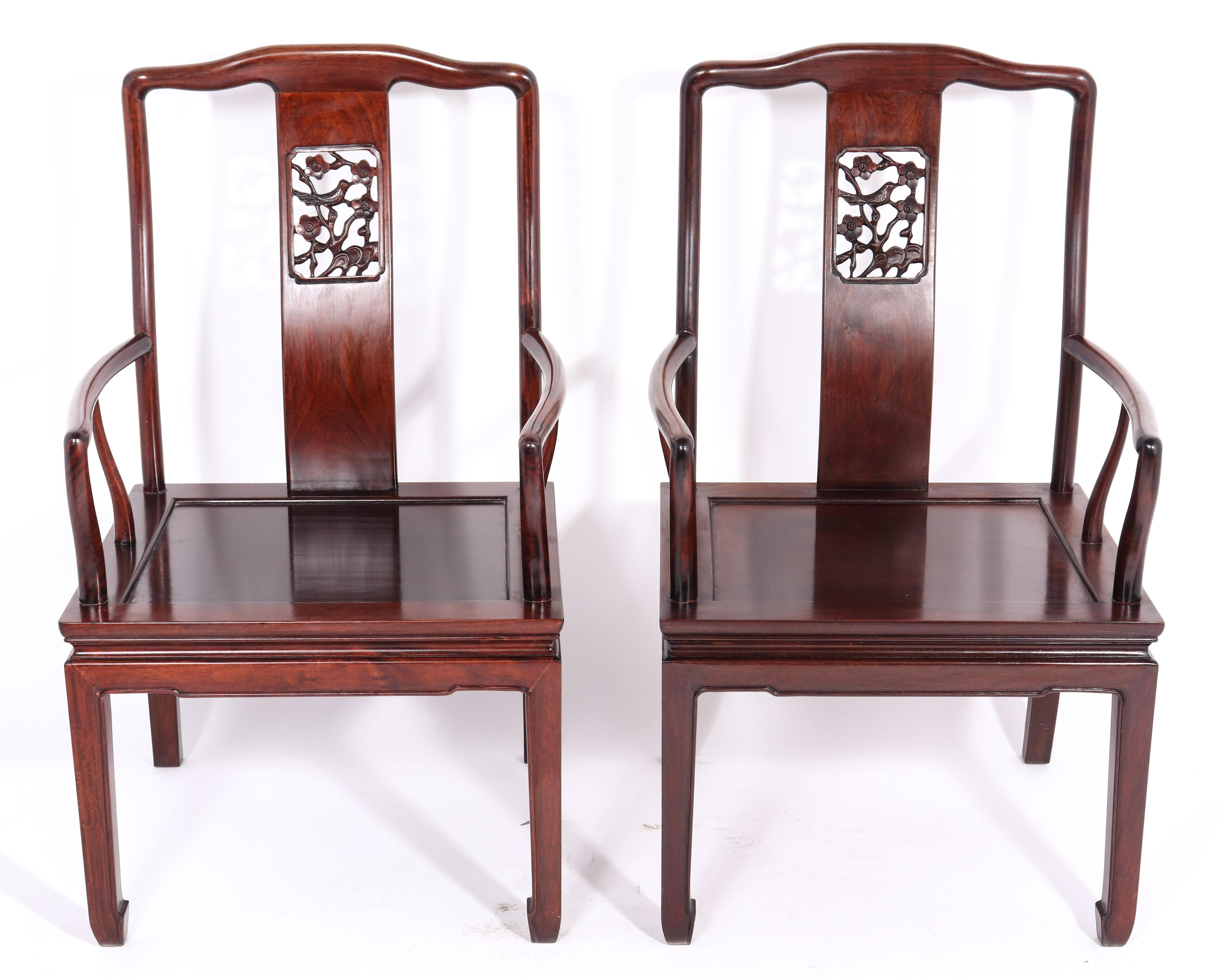 Pair of Chinese armchairs made in huanghuali hardwood. The pair has hand carved back plates with a bird sitting among flowers and decorative foliage. In great vintage condition with age-appropriate wear and use.