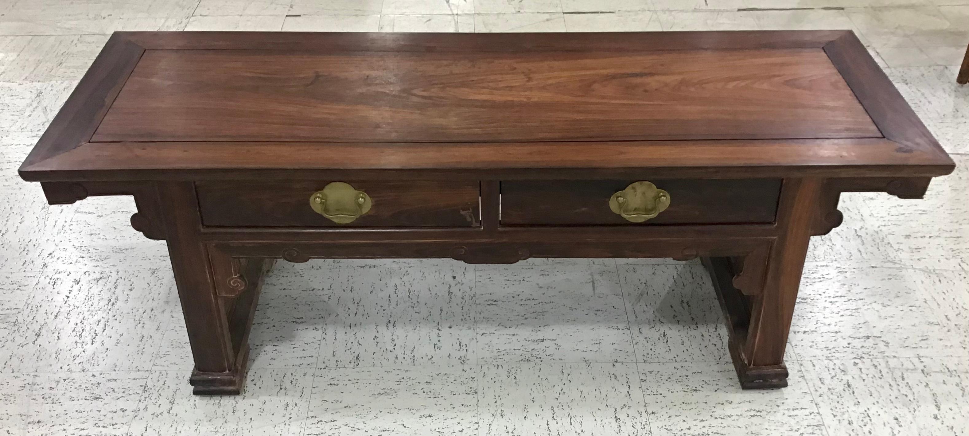 Chinese Huanghuali hardwood low table with drawers. The top surface with one large central plank framed by four side planks. Standing on straight legs ending in carved scrolls. Carved front side apron and side top supports. Two drawers mounted with