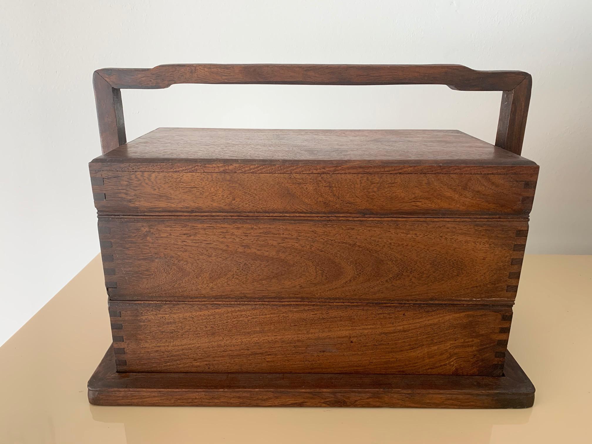 A Chinese Huanghuali picnic box with carrier frame featuring three removable stacking trays. It appears to be made with old Chinese rosewood (Huagnhuali) around 1950-1970s, possibly as diplomatic gift. The surface of the rose wood features
