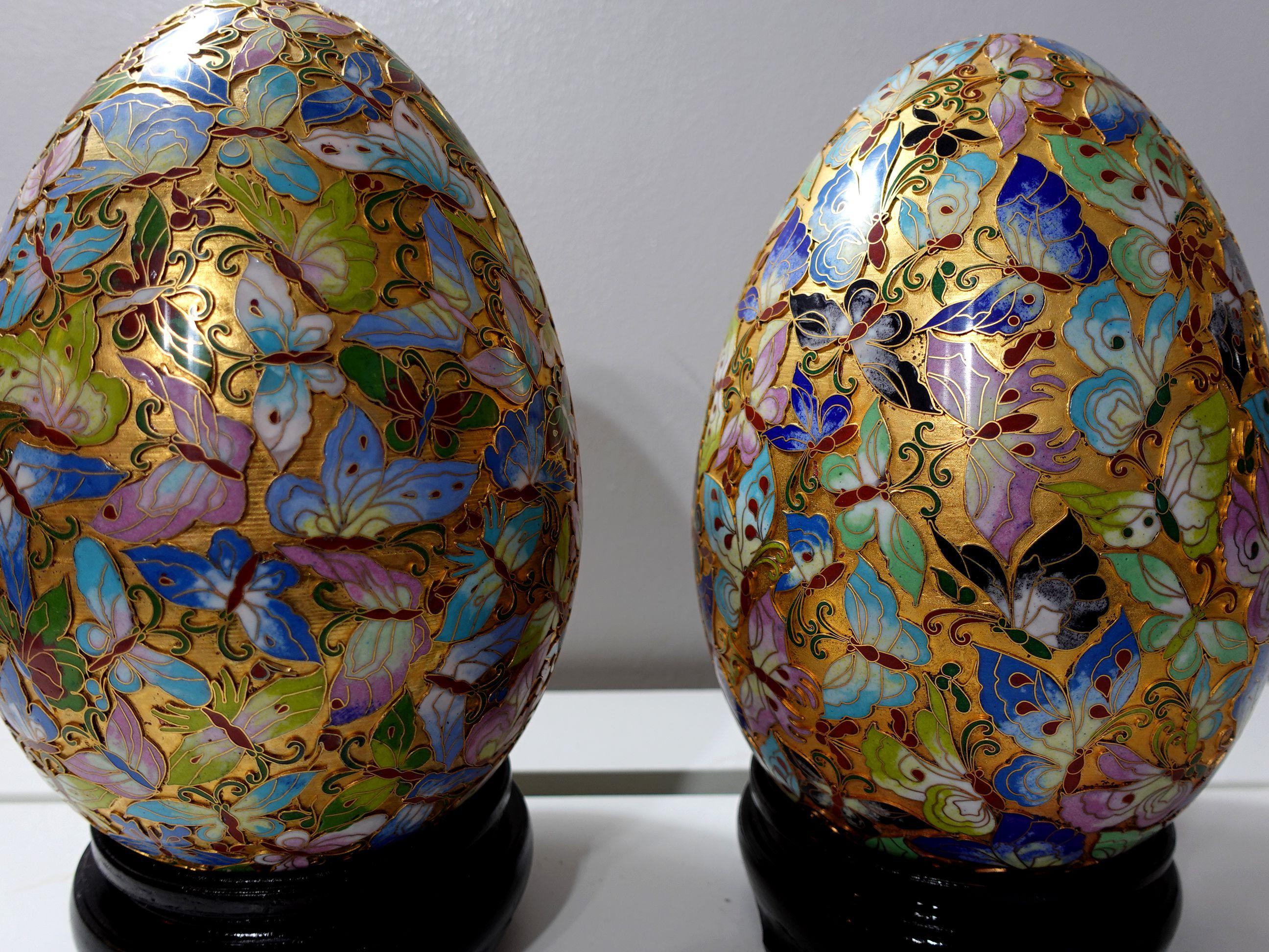 Presenting a pair of huge and beautiful Chinese cloisonné enamel eggs with intricated patterns of hundred butterflies made by hand seating on a wood stand, from the early 20 century. 
Dimensions: 11