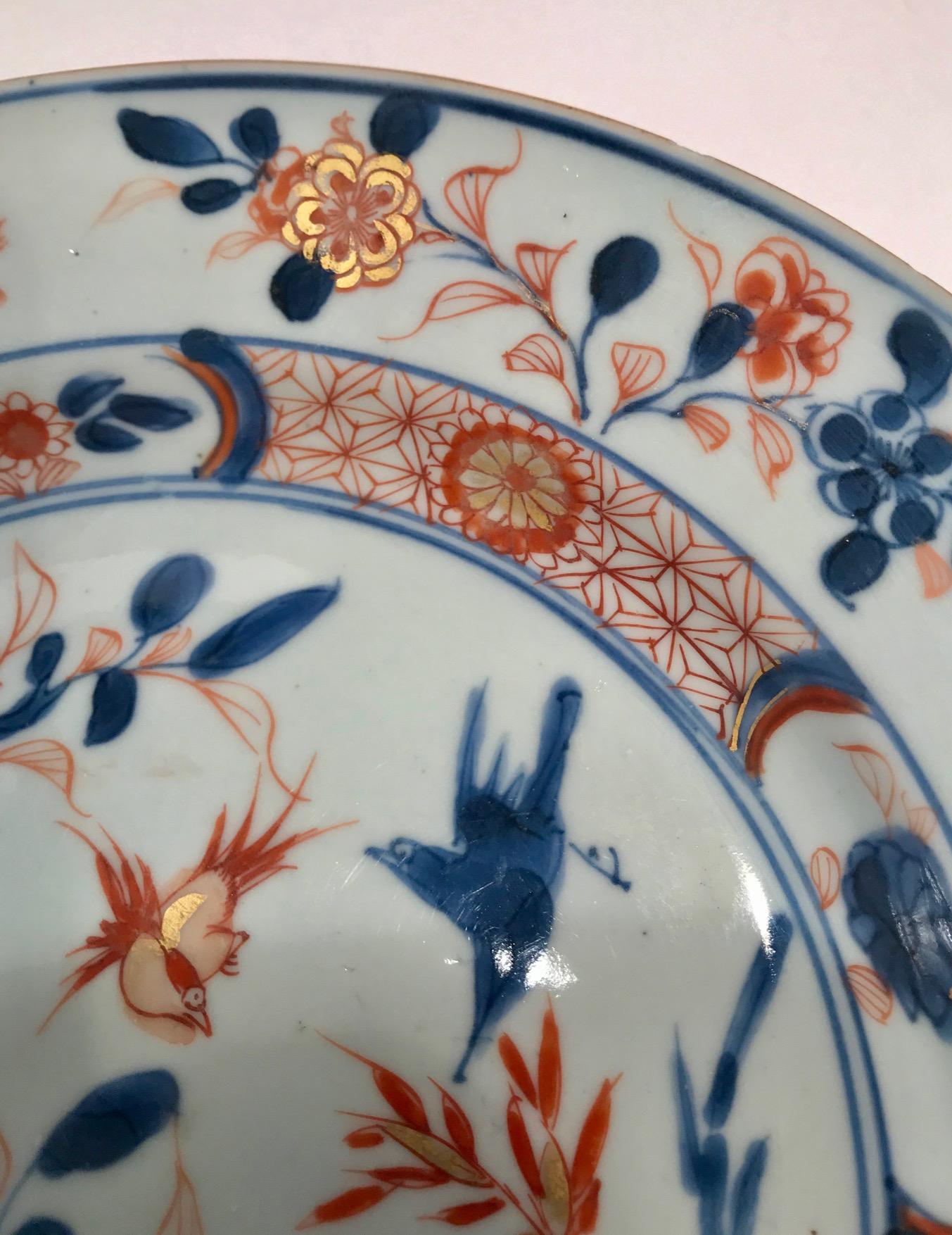 Beautiful eighteenth century deep Chinese export porcelain plate known as Chinese Imari. This piece is elegantly decorated first in an underglaze blue and then overpainted in iron red and gold that has not been rubbed off. Flowers and birds abound