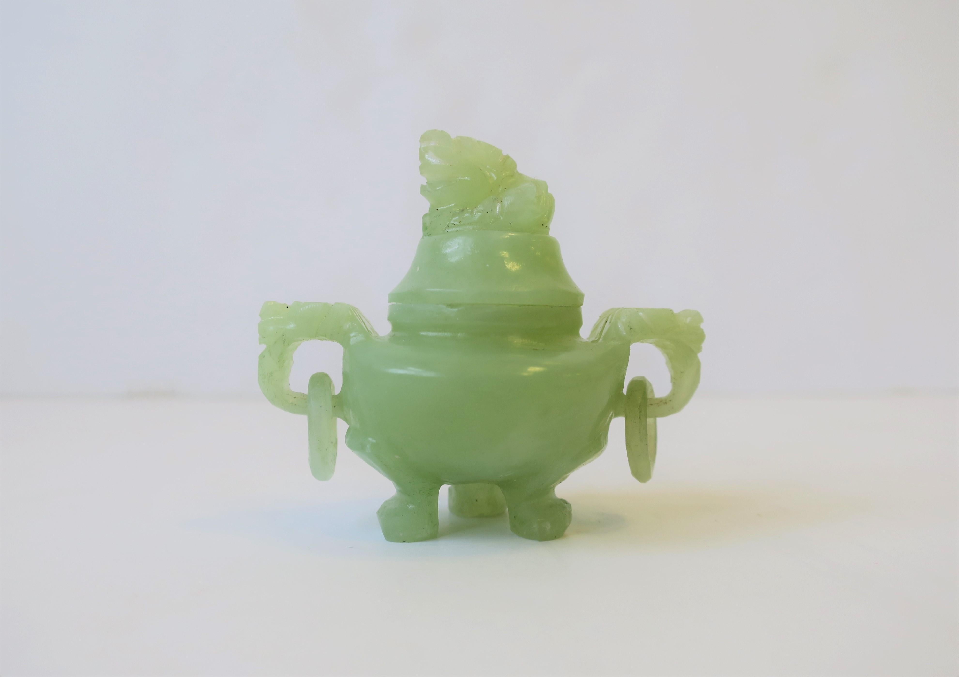 A small light green hue hard stone Chinese incense burner, circa 20th century, China. Incense burner has animal foo dog or lion hand carved design, loop handles, three foot/paw base and lid. Size perspective shown in image #3 next to car