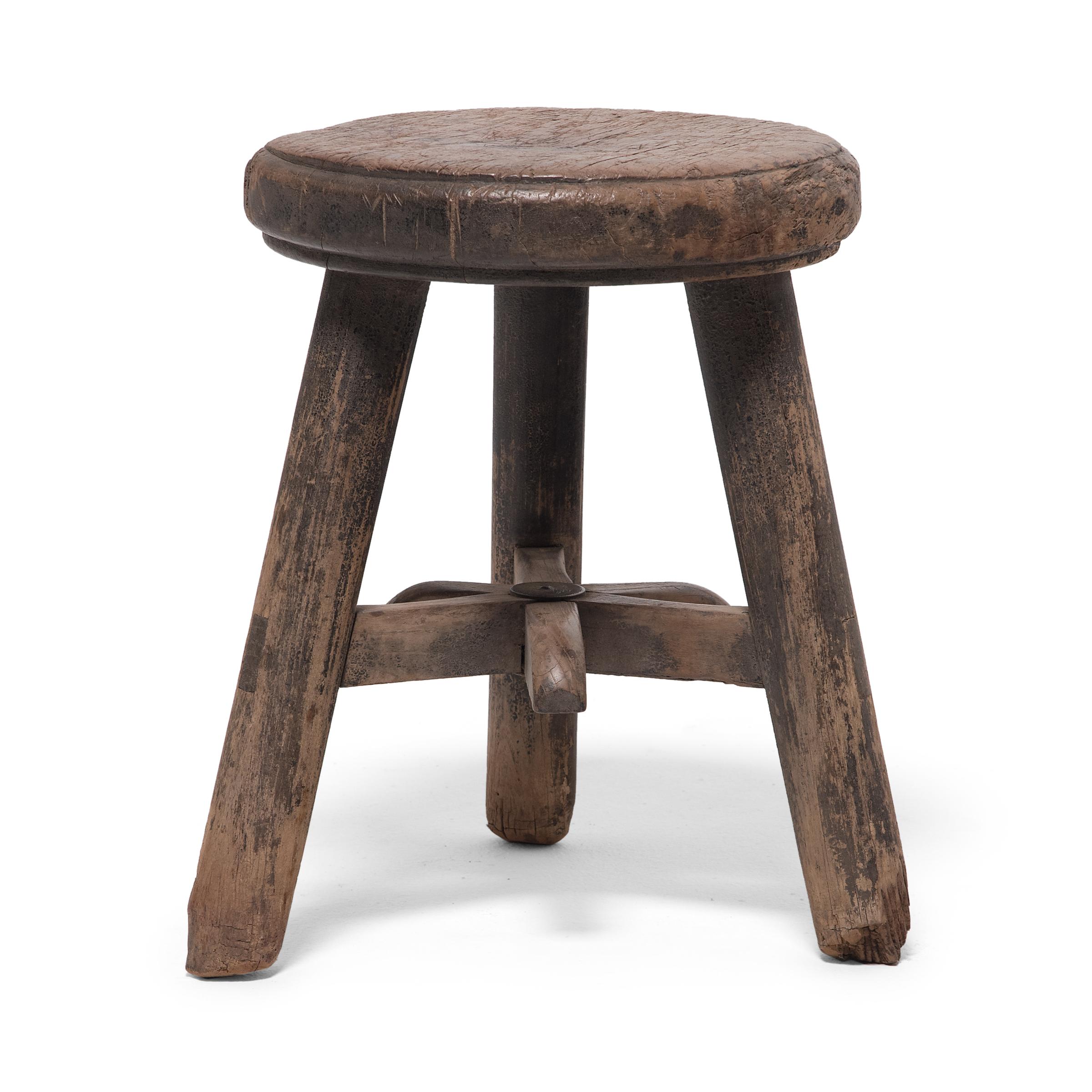 This 19th century stool from China's Shanxi province charms with its top-heavy form and fantastic texture. As evidenced by the many blade marks on its round top, this robust stool was doubled as a kitchen chopping block. The seat is supported by