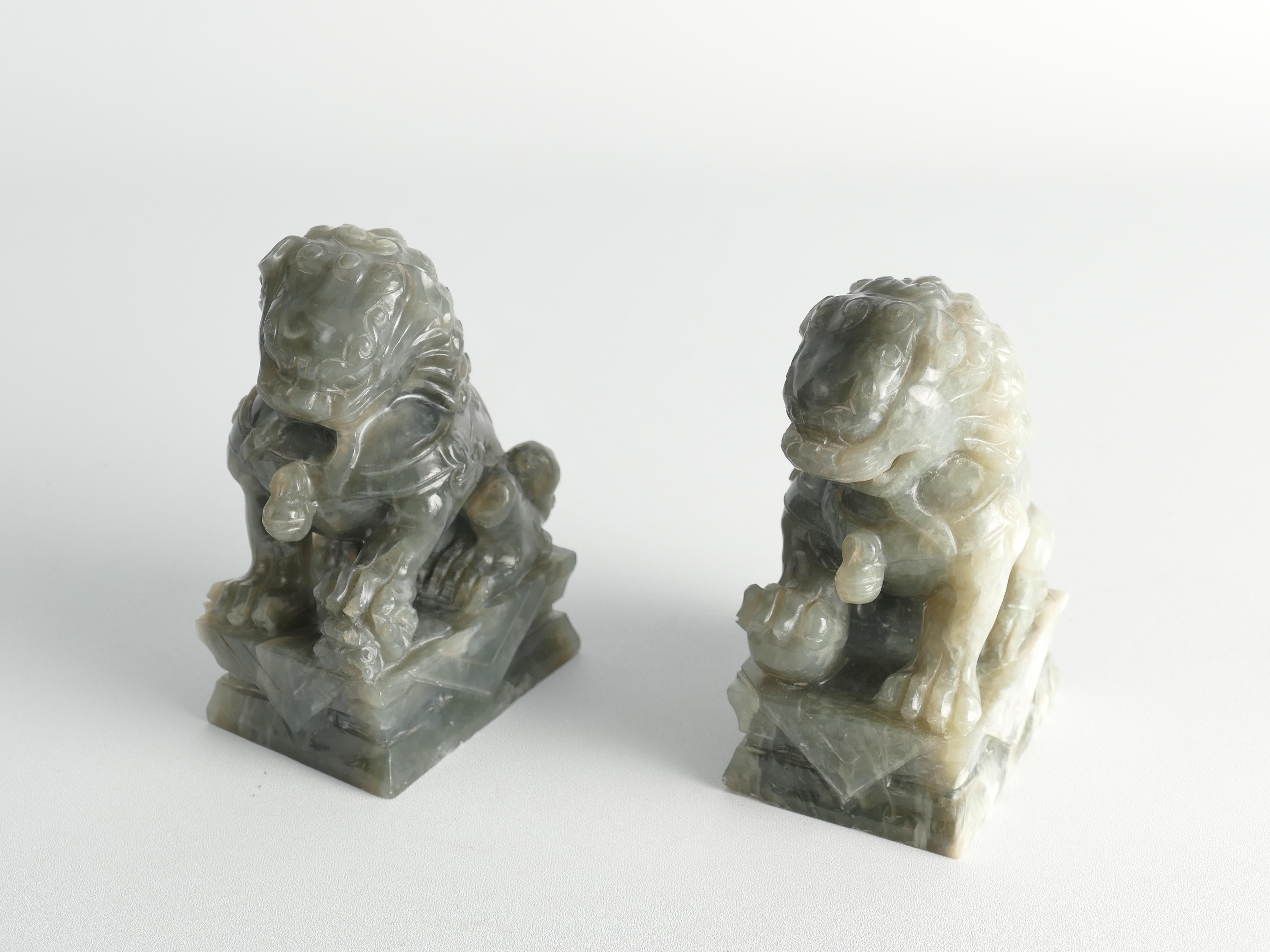 Chinese Jade Foo Dogs. The jade, or stone resembling its pale green hue,  beutifully exhibits shades that span from milky white to pale jade green.
The Foo Dogs possess a playful, lively appearance, each perched on its individual squared base. The