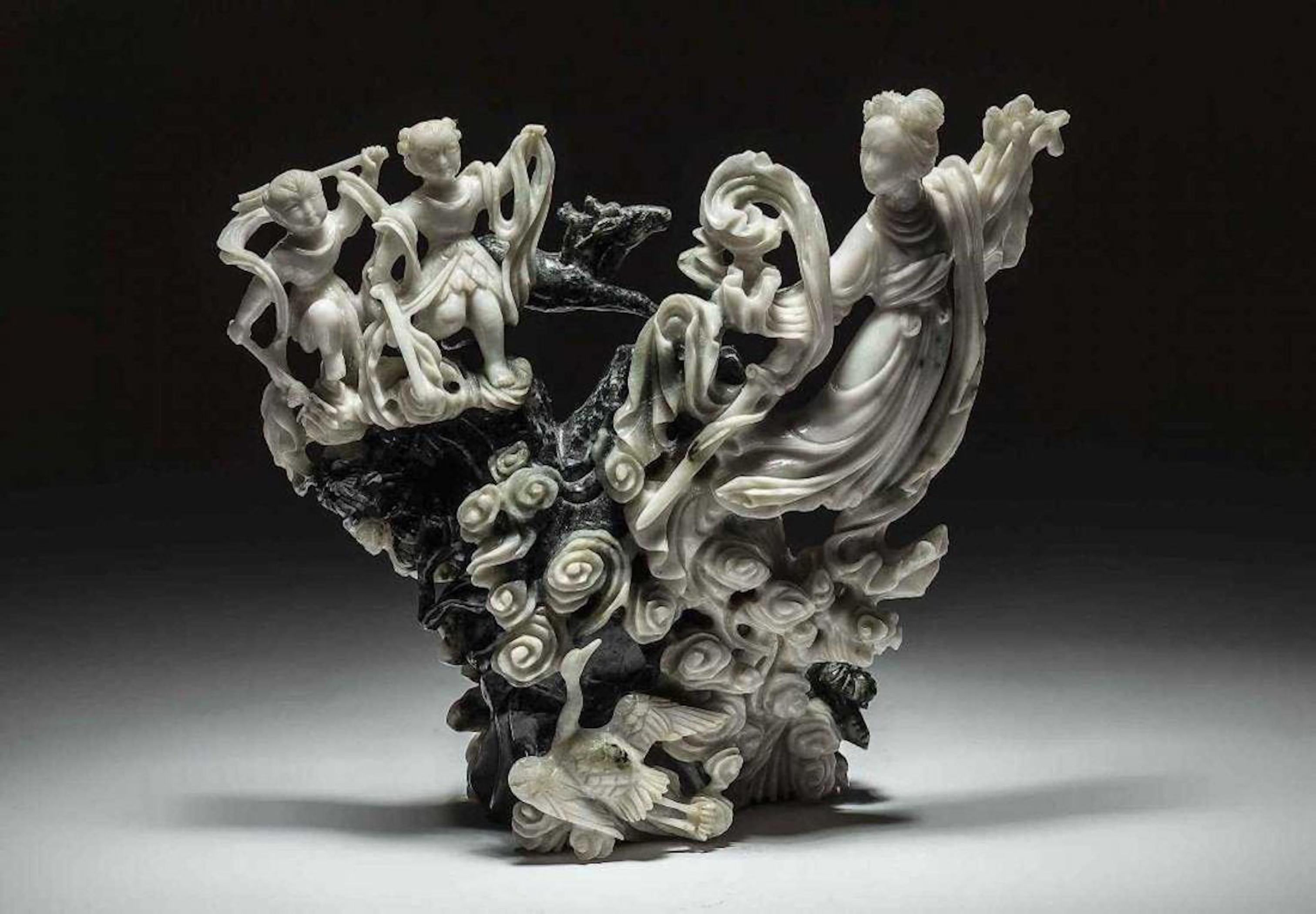  CHINESE JADE GROUP OF A FEMALE DEITY ASCENDING THE HEAVENS
The white jade deity with two young attendants amidst the clouds, before a spinach jade forested mountain with a leaping deer.

Height 6 ½ in., Width 7 ½ in.