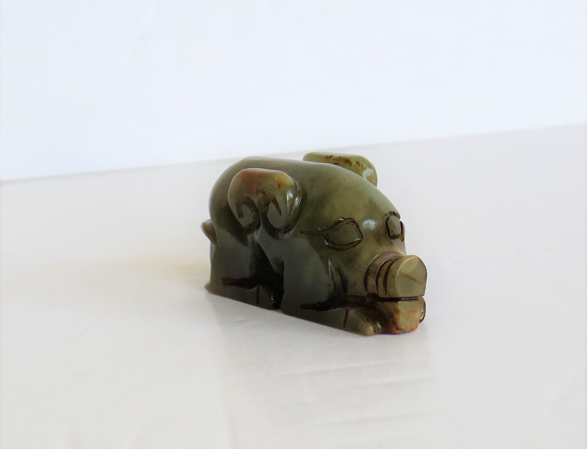 This is a Chinese natural jade, small hand carved stylized pig, possibly made as a talisman, which we date to the 19th century, Qing period.

This piece is made from natural Jade stone that is mainly a soft celadon green coloring with some shades