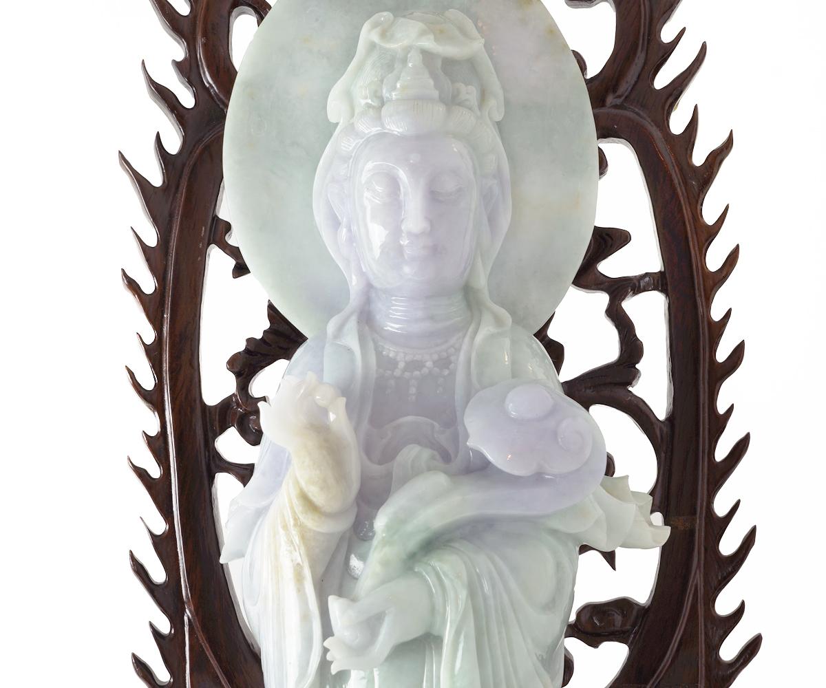 The colors on this wonderful jade quan yin include apple green with lavender, mauve and purple highlights. The quan yin has a wonderful face and is holding a Ruyi/scepter. The hand carved rosewood double lotus flower stand is intricately carved and