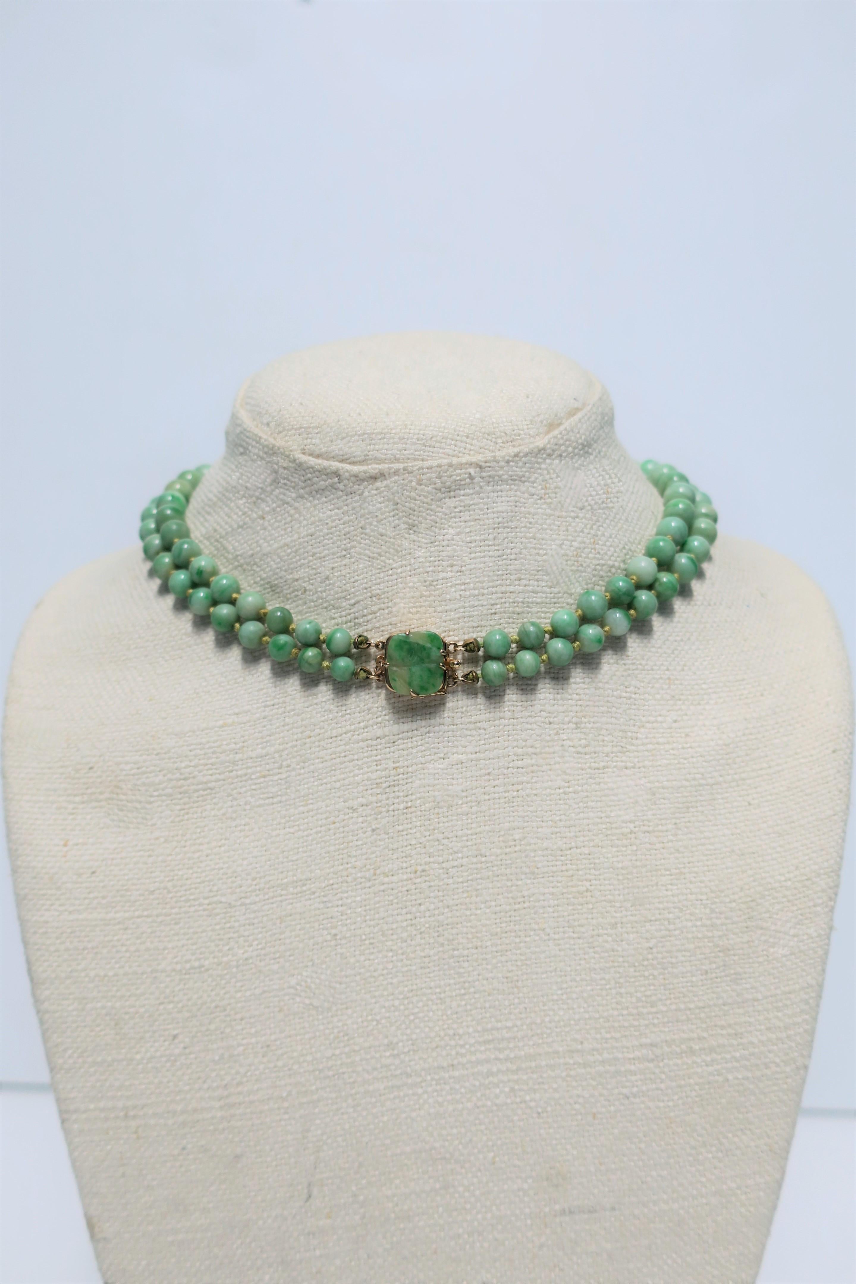A beautiful double strand graduated Chinese green jadeite and 14-karat gold necklace, circa 1940s China. Necklace clasp is a carved green jadeite floweret and 14-karat yellow gold. This double strand is strung beautifully in light green silk string