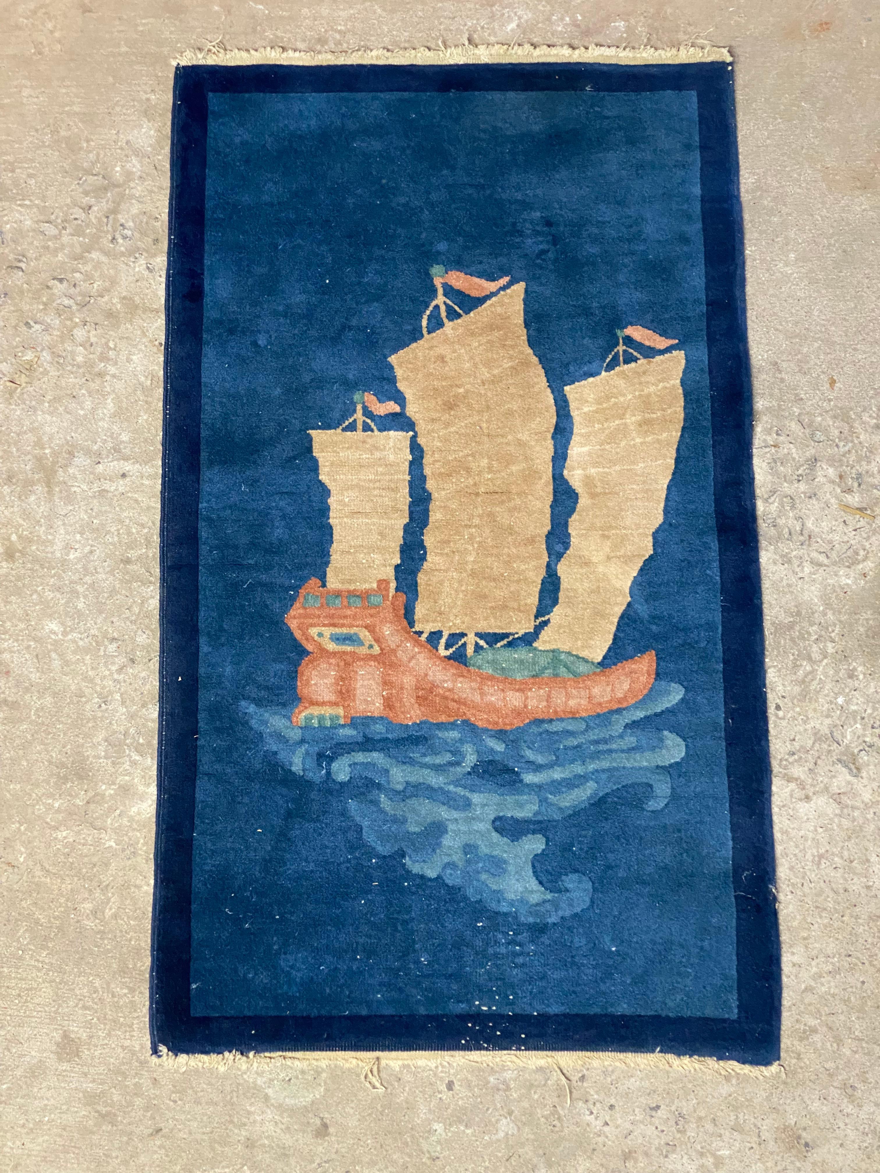 Fantastic wool Chinese Deco rug depicting a distinctive masted Chinese Junk ship on a deep blue background. A wonderful accent piece for anywhere in the home or office. Circa 1930-40. Good overall condition with some minor fade due to age, wear and