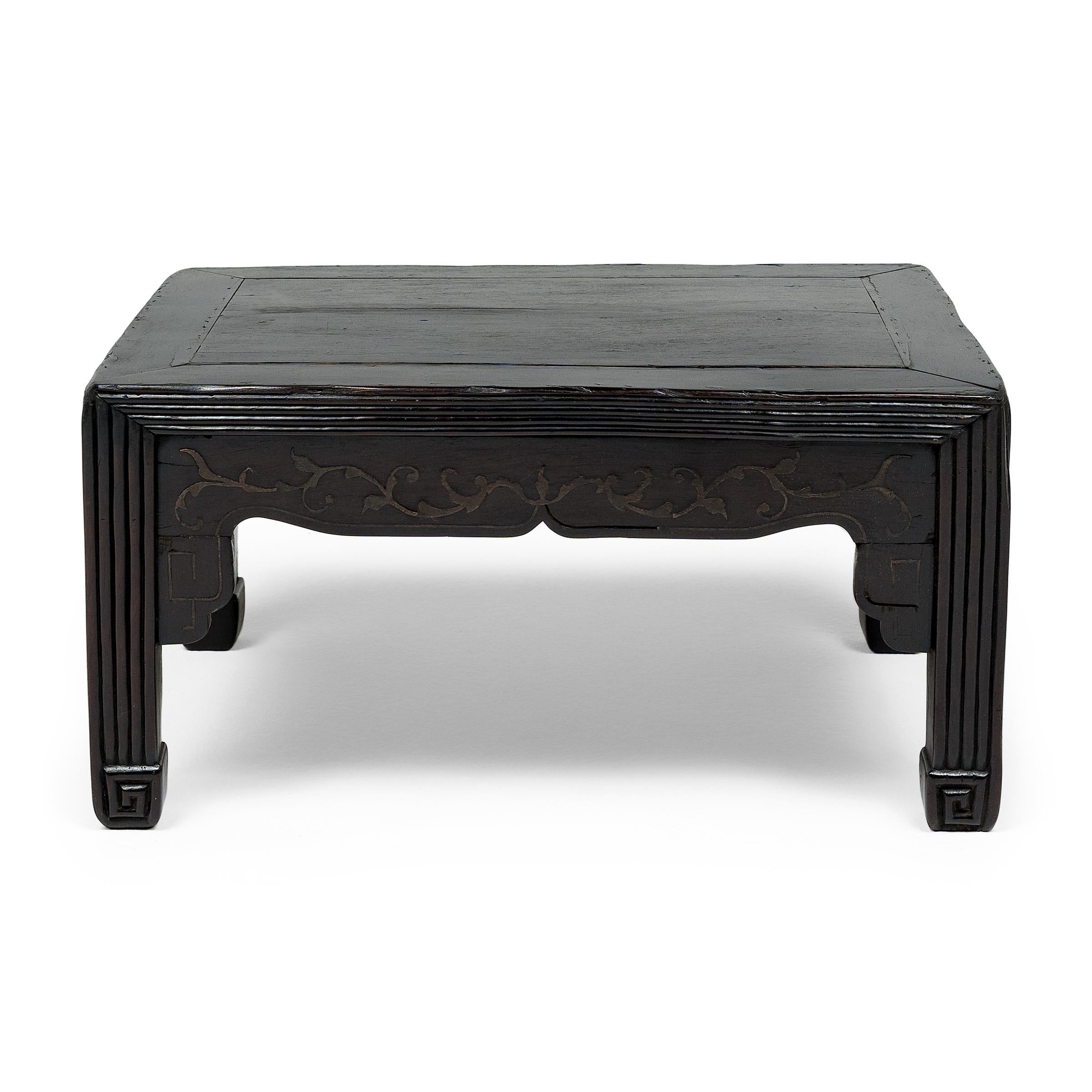 This 19th-century hardwood kang table was traditionally used as a convenient working surface for painting, writing, sewing, or eating atop a heated kang platform. The petite table features a rectangular floating-panel top, straight legs and a simple