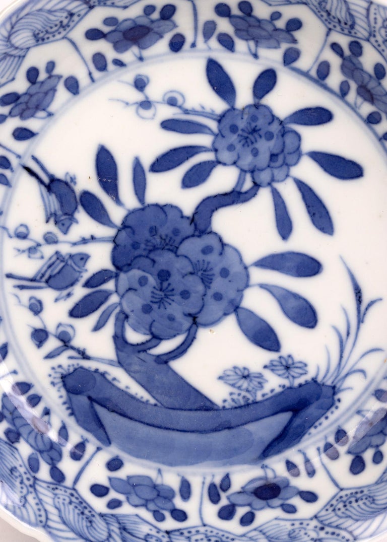 A very fine antique Chinese Kangxi floral painted blue and white porcelain dish dating between 1661 and 1722. The lightly made dish is of round form with a raised fluted rim and is decorated to the centre with two small birds descending on a