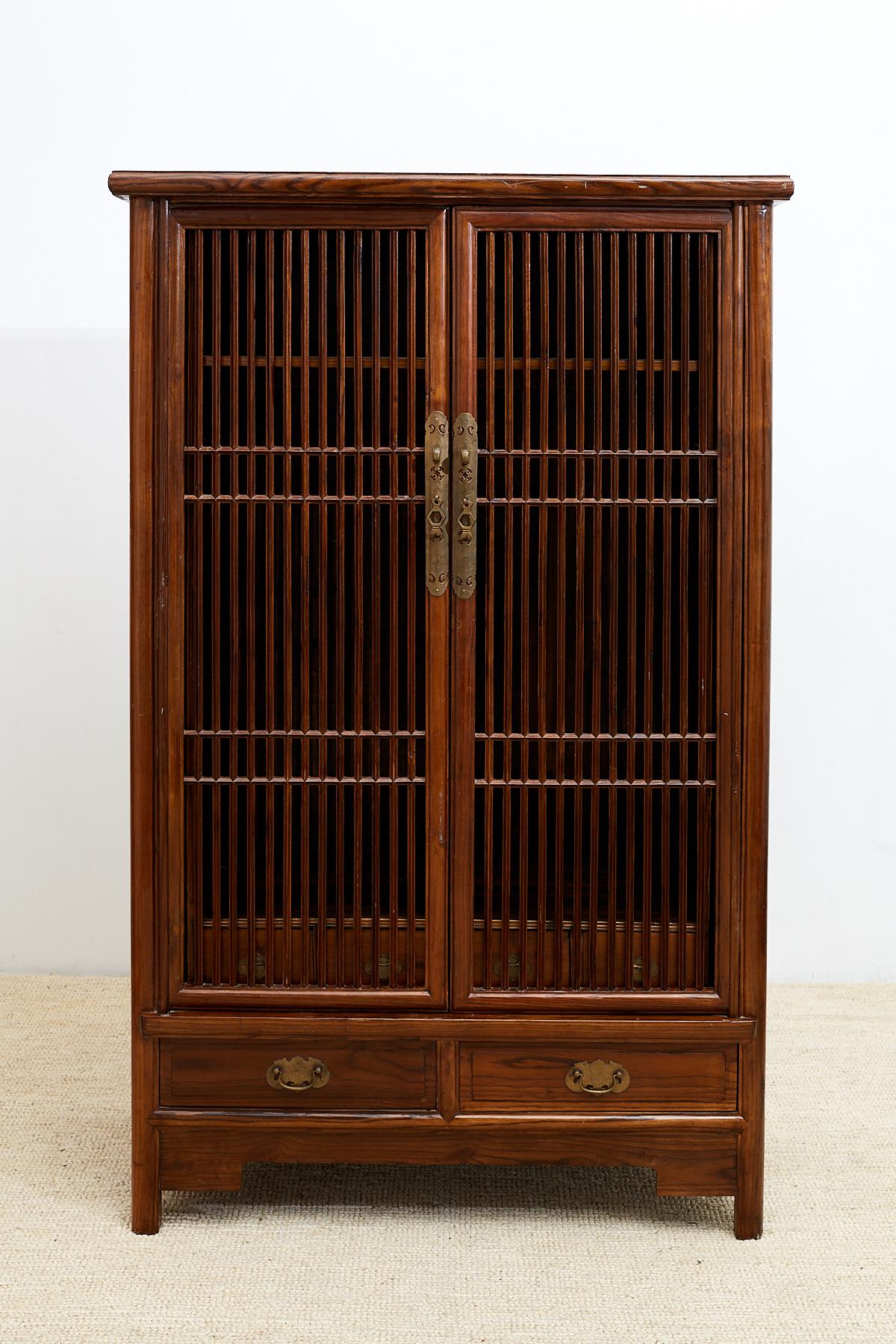 Distinctive Chinese kitchen cabinet featuring beautifully hand-carved lattice doors with a geometric design. Each front door opens and slides into the case where they are hidden from view. The inside has a large two shelf storage area and four small