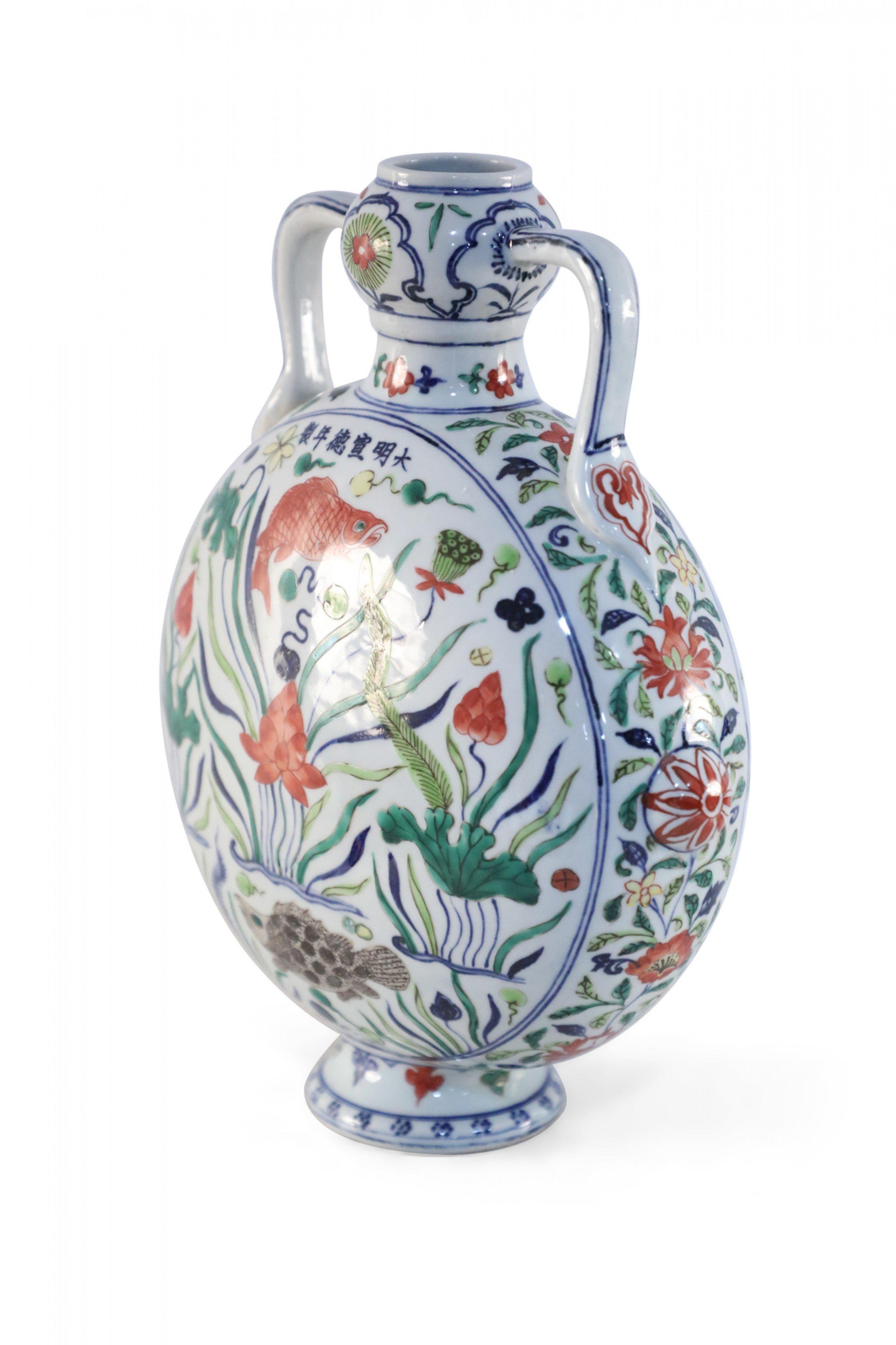 Antico vaso cinese (inizio XX secolo) in porcellana bianca a forma di fiasco di luna, decorato con una scena subacquea di alghe, koi e tartarughe circondate da fiori e sormontato da due manici.

Condit: Buono; Usura coerente con l'età e l'utilizzo