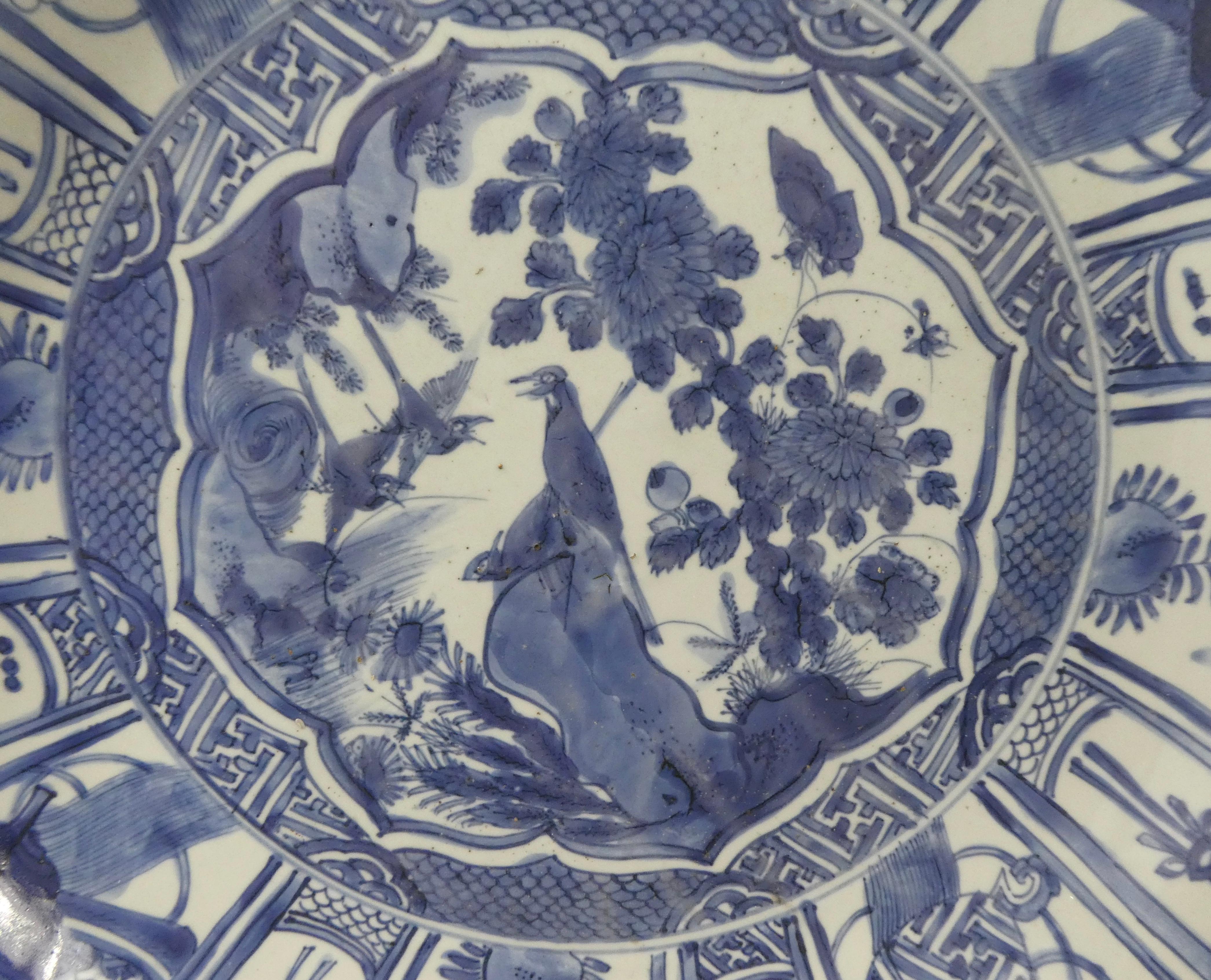 A large Chinese porcelain ‘Kraak’ charger, Wanli Period (1573-1619) Late Ming. Painted in underglaze blue, to the centre, with a panel of birds perched on rocks, amongst flowering plants, whilst two further bird fly above. Surrounded by a border of