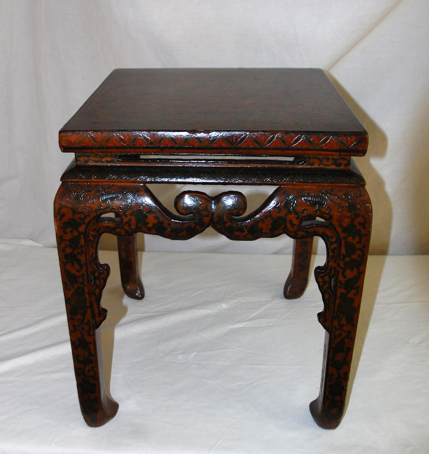 Chinese Qing Dynasty, Kuang Hsu period lacquered hand painted square waisted stool with carved double scroll skirt. This handsome stool is painted on all visible services with scrolling leaves and flowers primarily in muted greens. The center focus