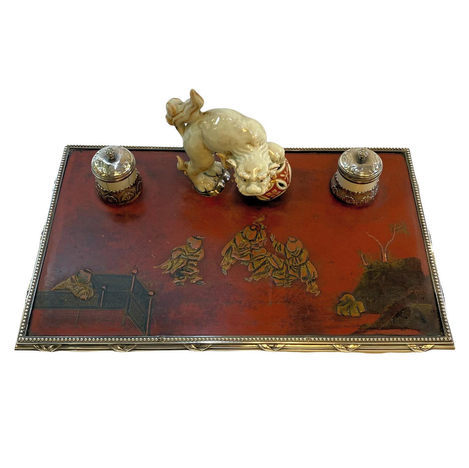 Our charming inkwell features a finely sculpted porcelain foo dog standing on lacquered wooden panel with two silver ink vessels with their original porcelain cups.  Hinge of one well is broken, but does rest nicely on its vessel and certainly could