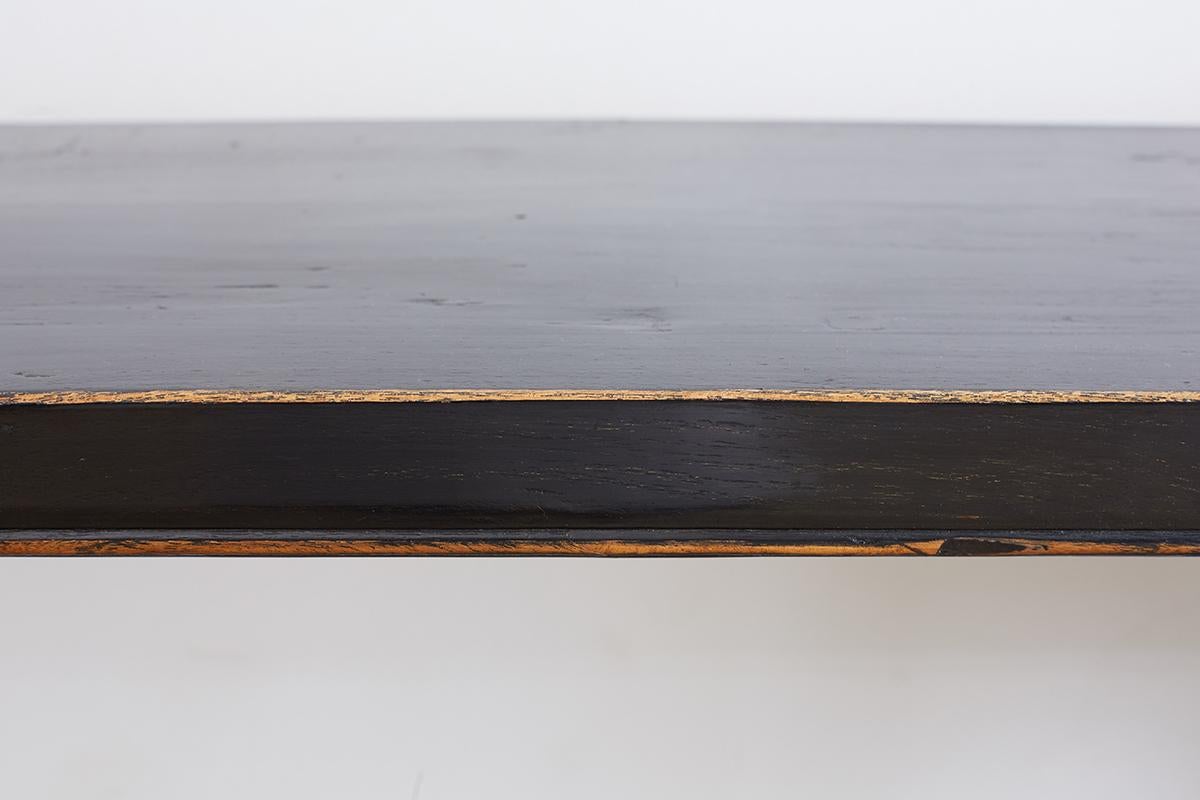Elegant Chinese black lacquered console or sofa table made in the altar style with scrolled feet. Features a rich, distressed lacquer finish constructed from elm. Each leg has a decorative oval opening and ends with a scroll. The thick solid slabs