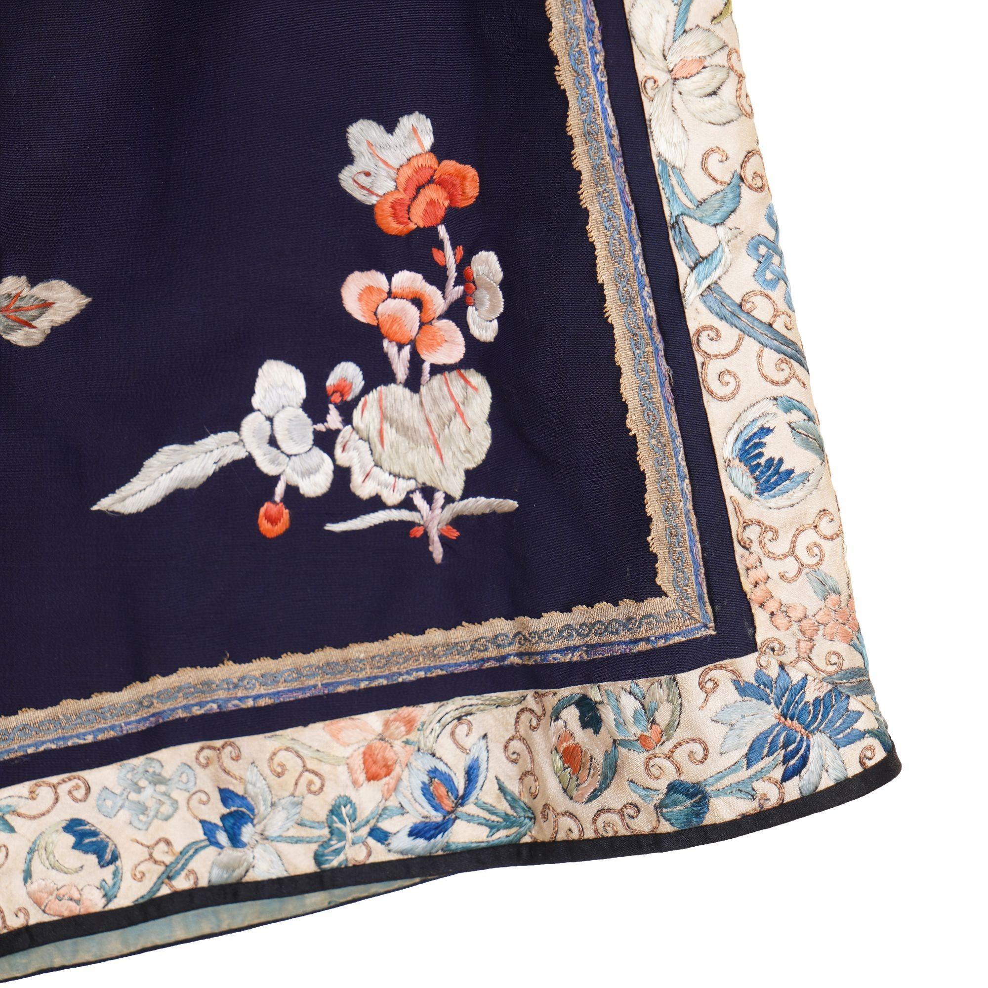 Chinesische navyblaue Seiden-Kurzjacke mit Blumenstickerei. Die Jacke ist vorne geknöpft, hat schwarze Paspeln und Knöpfe und weite Ärmel. Das applizierte runde Kragenband ist aus schwarzer Seide und mit rosa und blauen Blumen und grünem Laub
