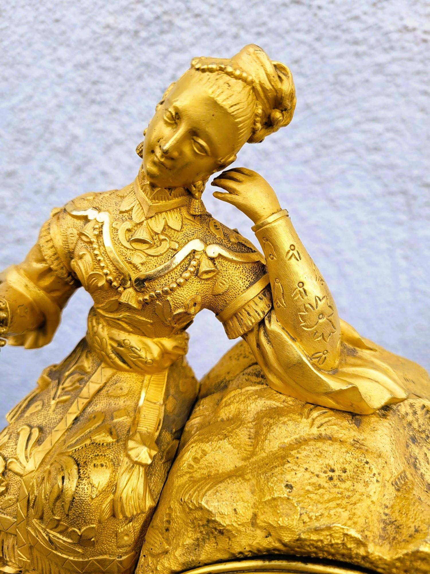 Ormulu bronze clock representing a Chinese woman with a bird perched on her hand

Note the quality of the gilding but also the chiseling which reveals many details: fine and delicate face, embroidery of the dress, jewels, and the flower