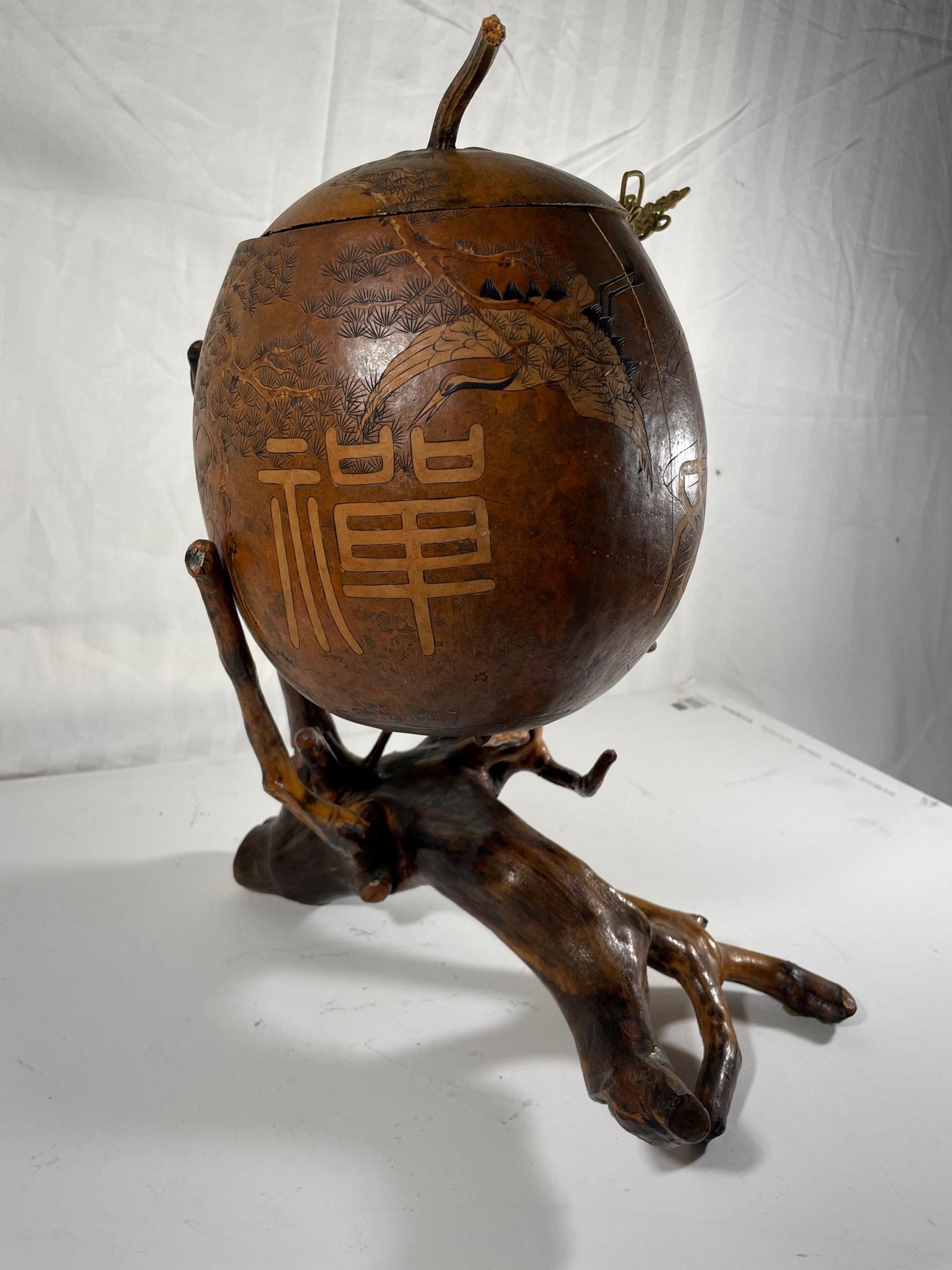 Chinese Lanzhou Gourd carving with macrame cord on root stand sculpture.

Early 20th century large engraved and carved Chinese Lanzhou gourd. Dramatic design with symbols and letters, executed in a delicate technique on the surface of the gourd.