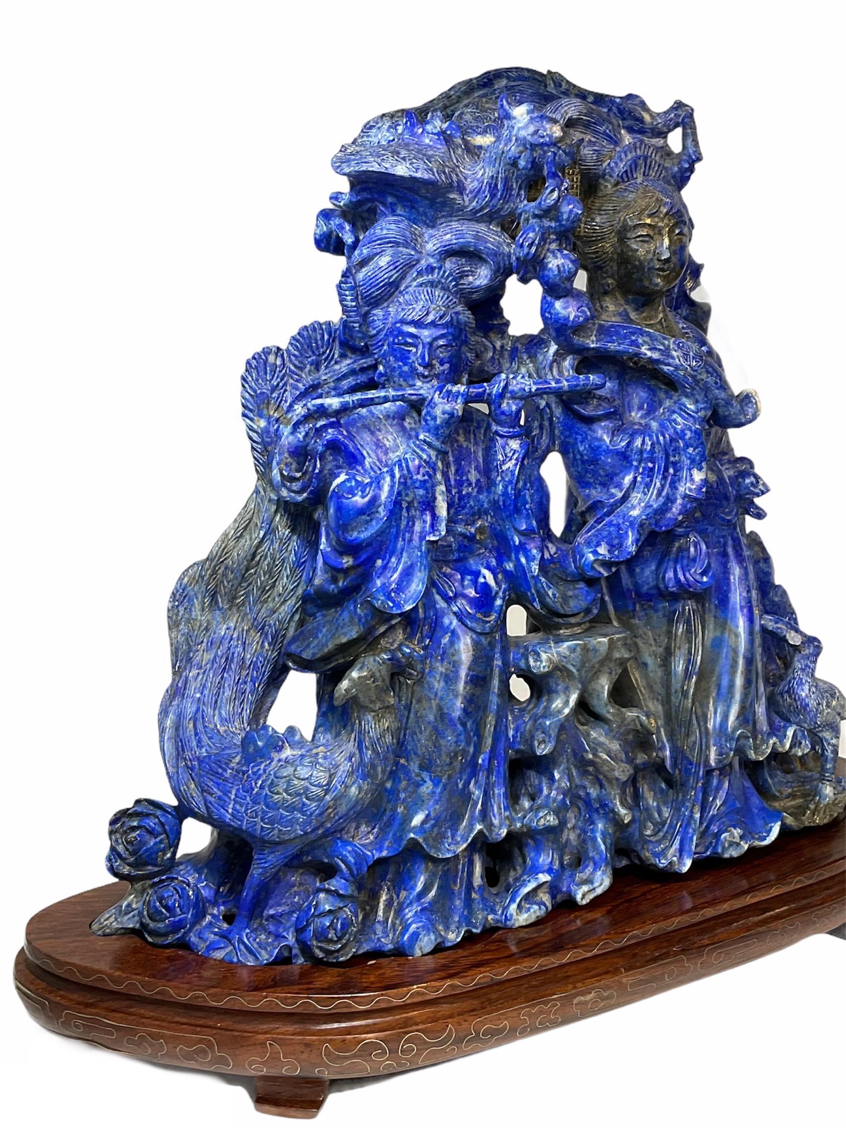 This is a large heavy Chinese lapis lazuli well carved in details group of figures sculpture.`It depicts two young ladies very well dressed in southern and northern dynasty clothes with traditional Chinese hair styles standing up between a tree