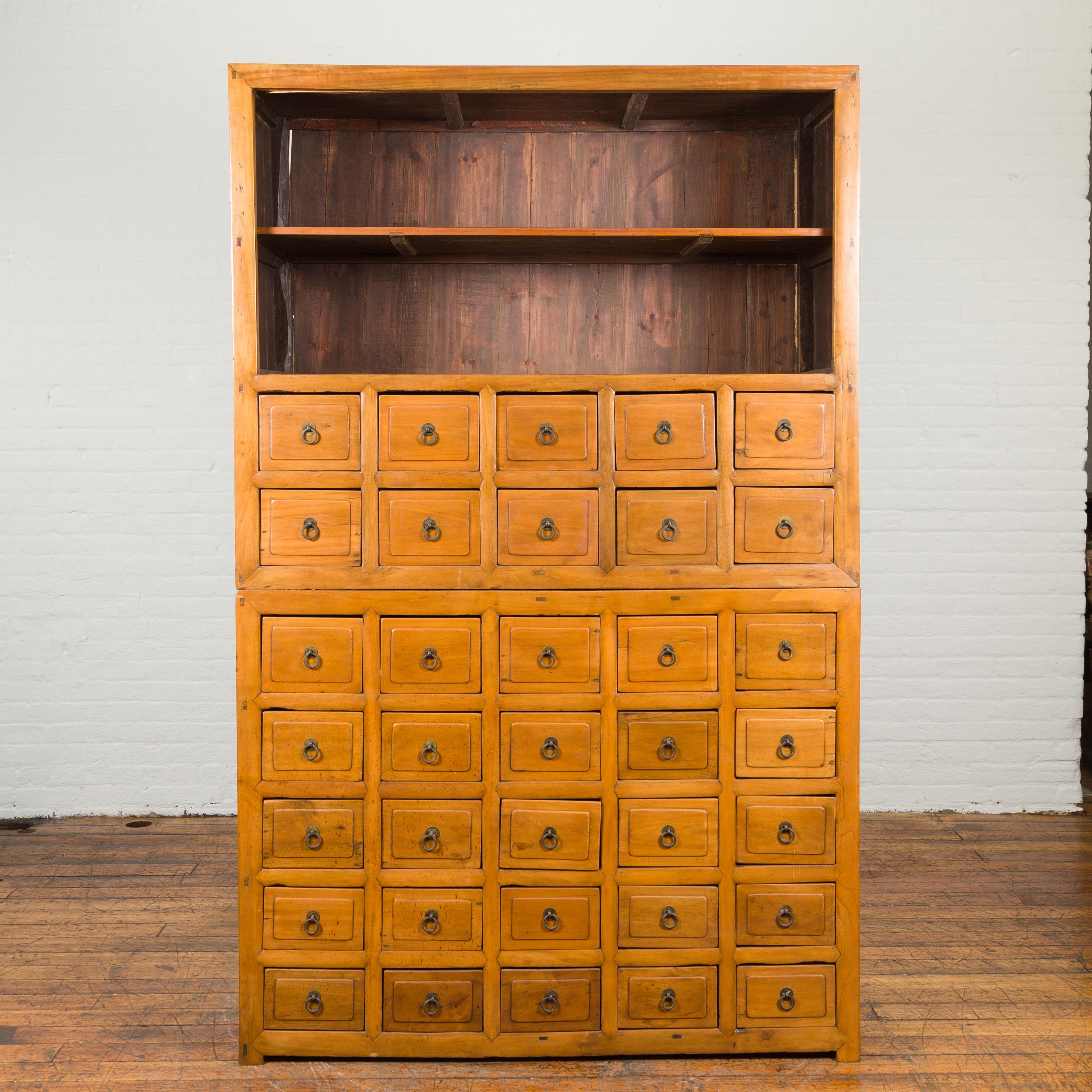 A Chinese Qing Dynasty period late 19th century apothecary merchant's cabinet made in two parts of nam wood (a variety of cedar) with shelves and multiple drawers. Created in China during the Qing Dynasty period, this cabinet features 35 drawers