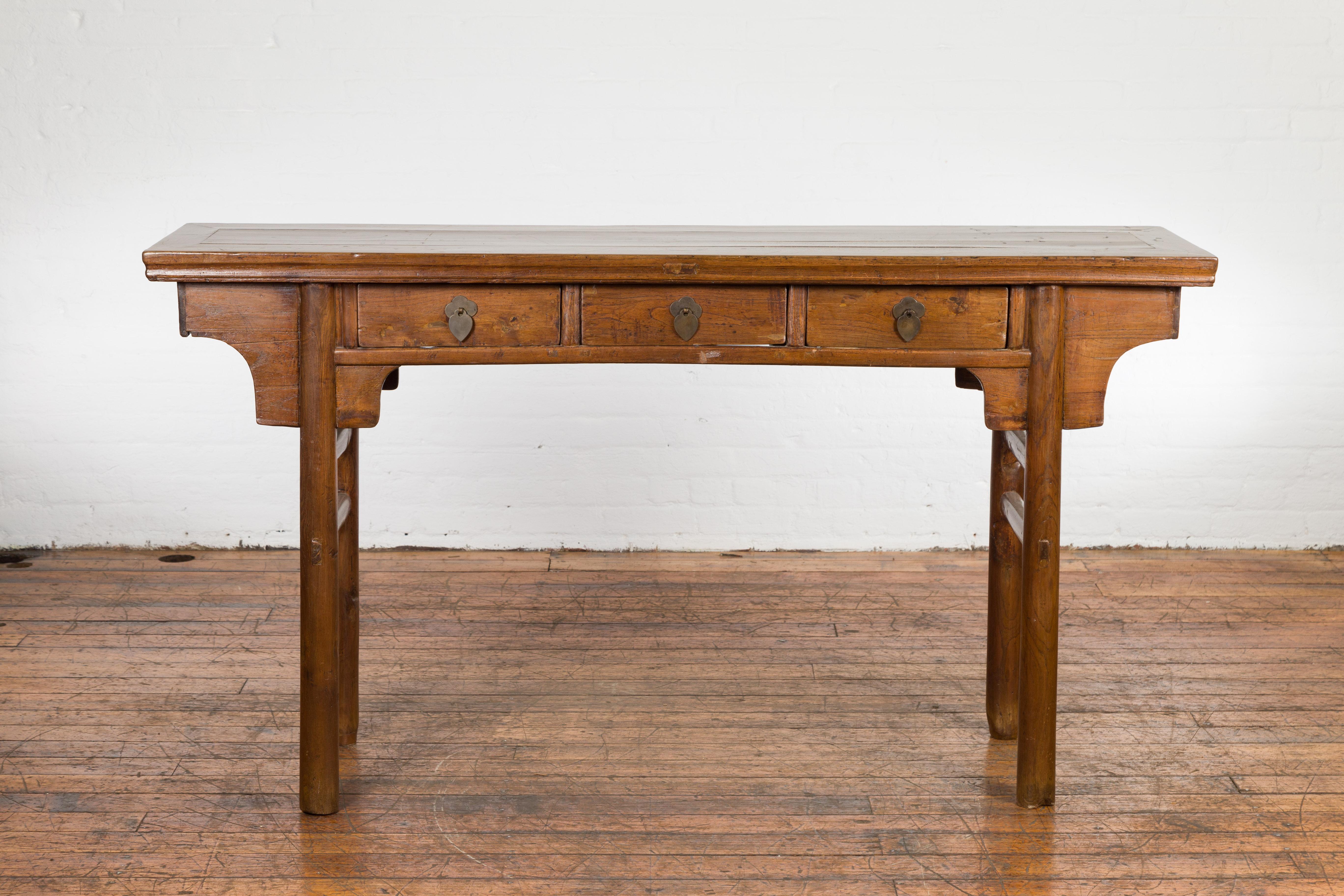 An antique Chinese late Qing Dynasty period wooden altar console table from the early 20th century, with three drawers and side stretchers. Created in China during the early years of the 20th century, this wooden altar console table features a long