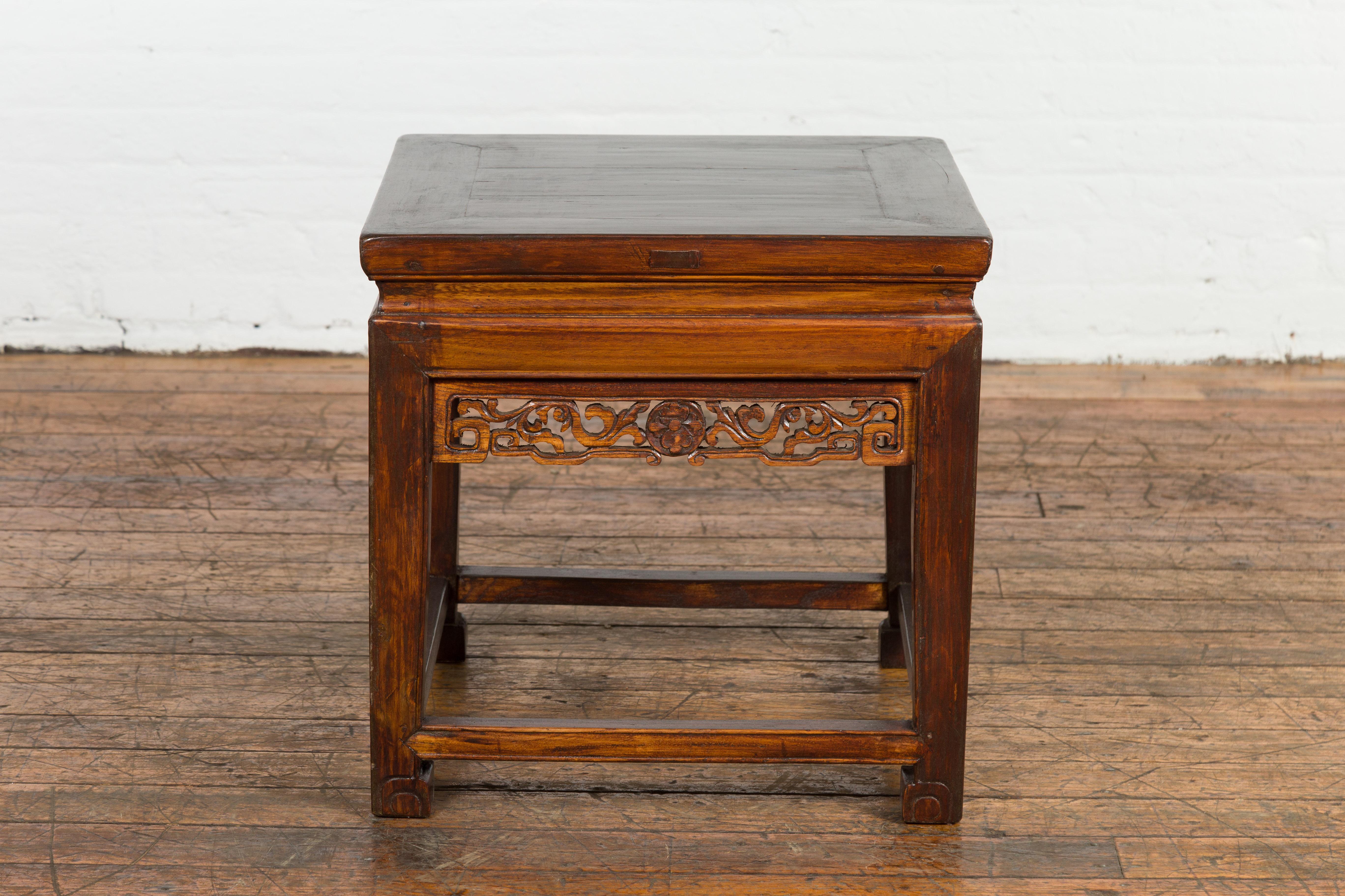 A Chinese late Qing Dynasty period side table from the early 20th century with carved apron and scrolling feet. Infusing both utility and aesthetics, this Chinese late Qing Dynasty period side table from the early 20th century effortlessly strikes a