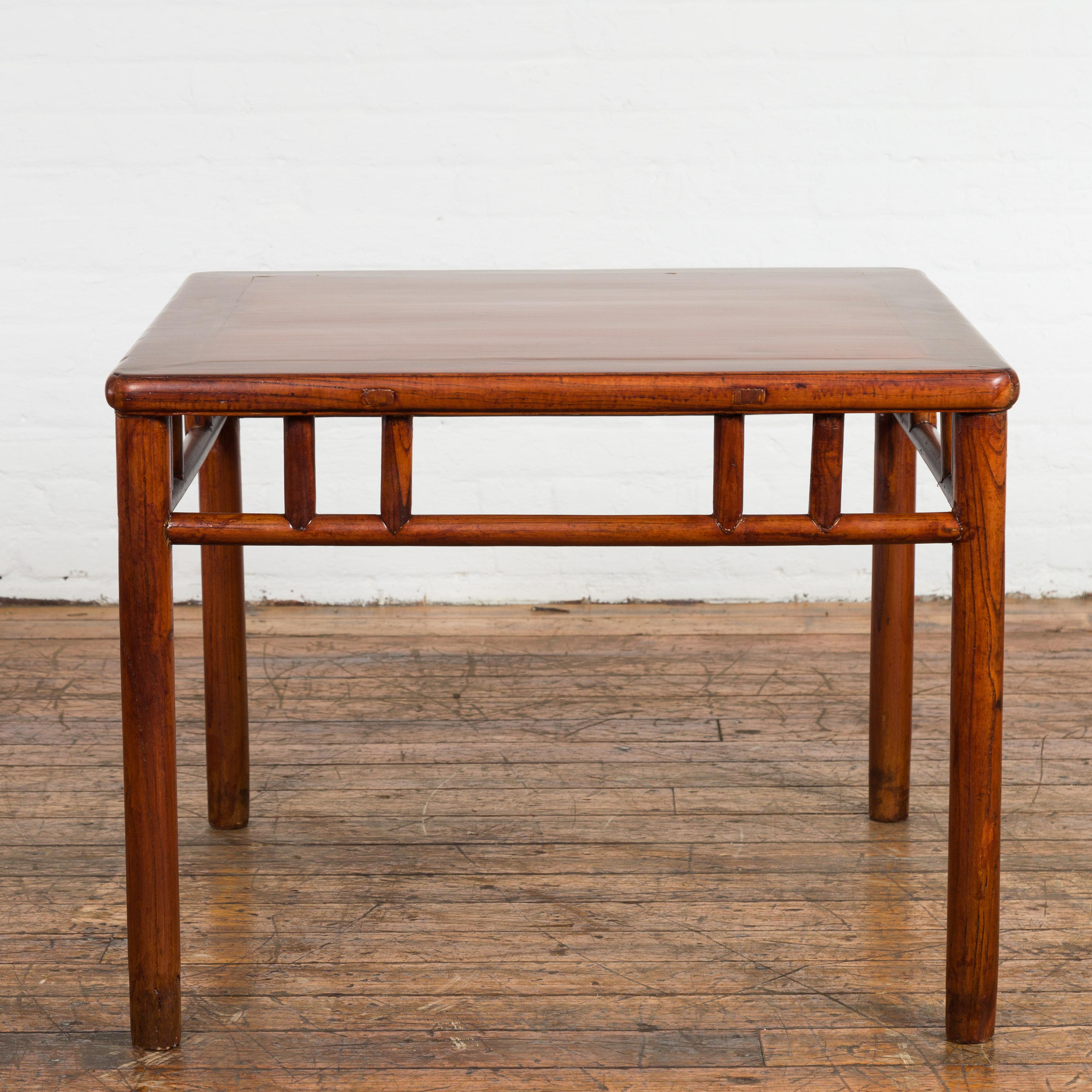 A Chinese late Qing Dynasty period side table from the early 20th century with square top, open apron, pillar strut motifs and cylindrical legs. Created in China during the late Qing Dynasty period in the early years of the 20th century, this wooden