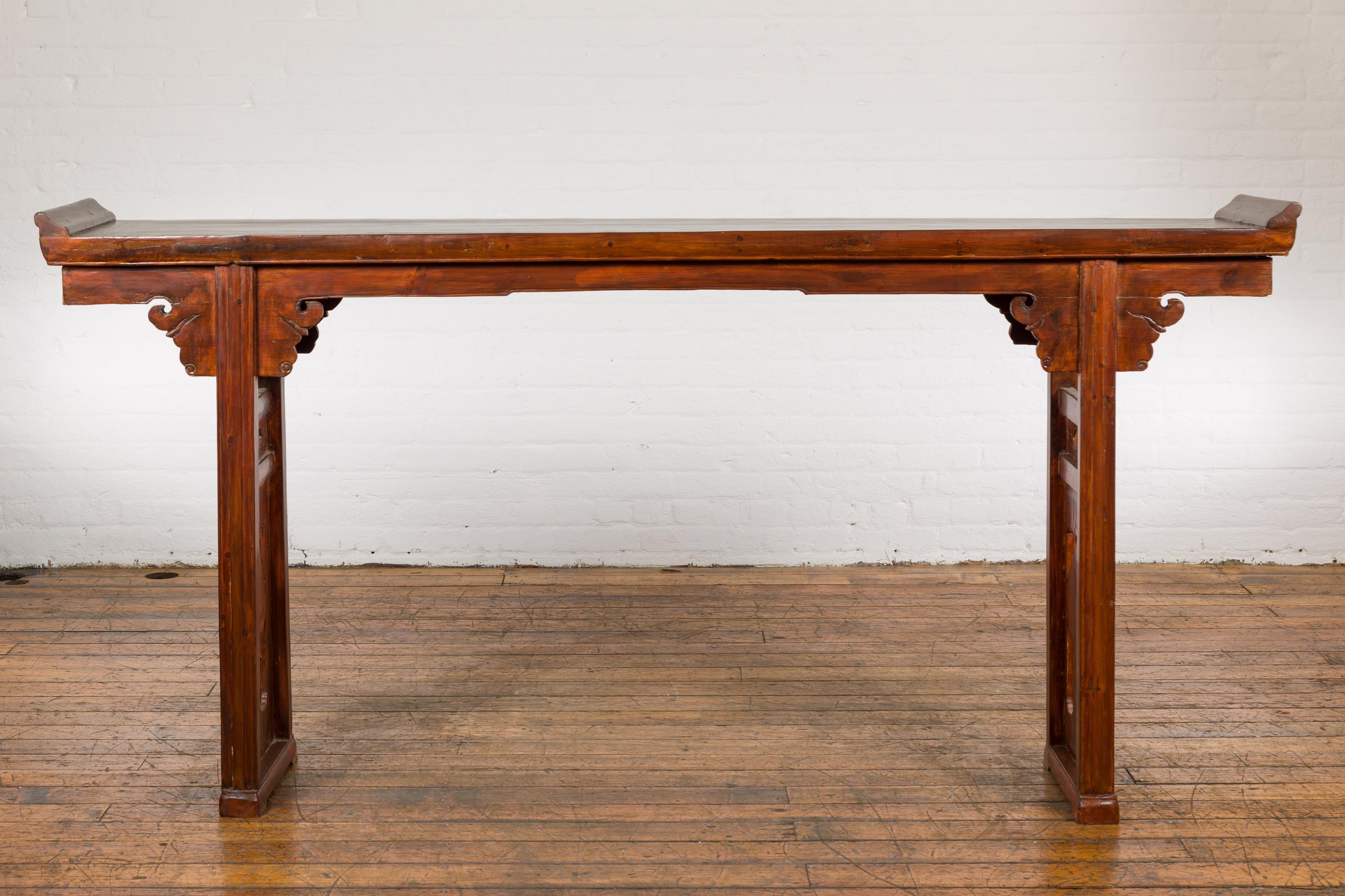 A long Chinese late Qing Dynasty period carved wooden altar console table from the early 20th century, with everted flanged and carved sides adorned with pierced trees motifs. Elevate your interior design with this long Chinese late Qing Dynasty