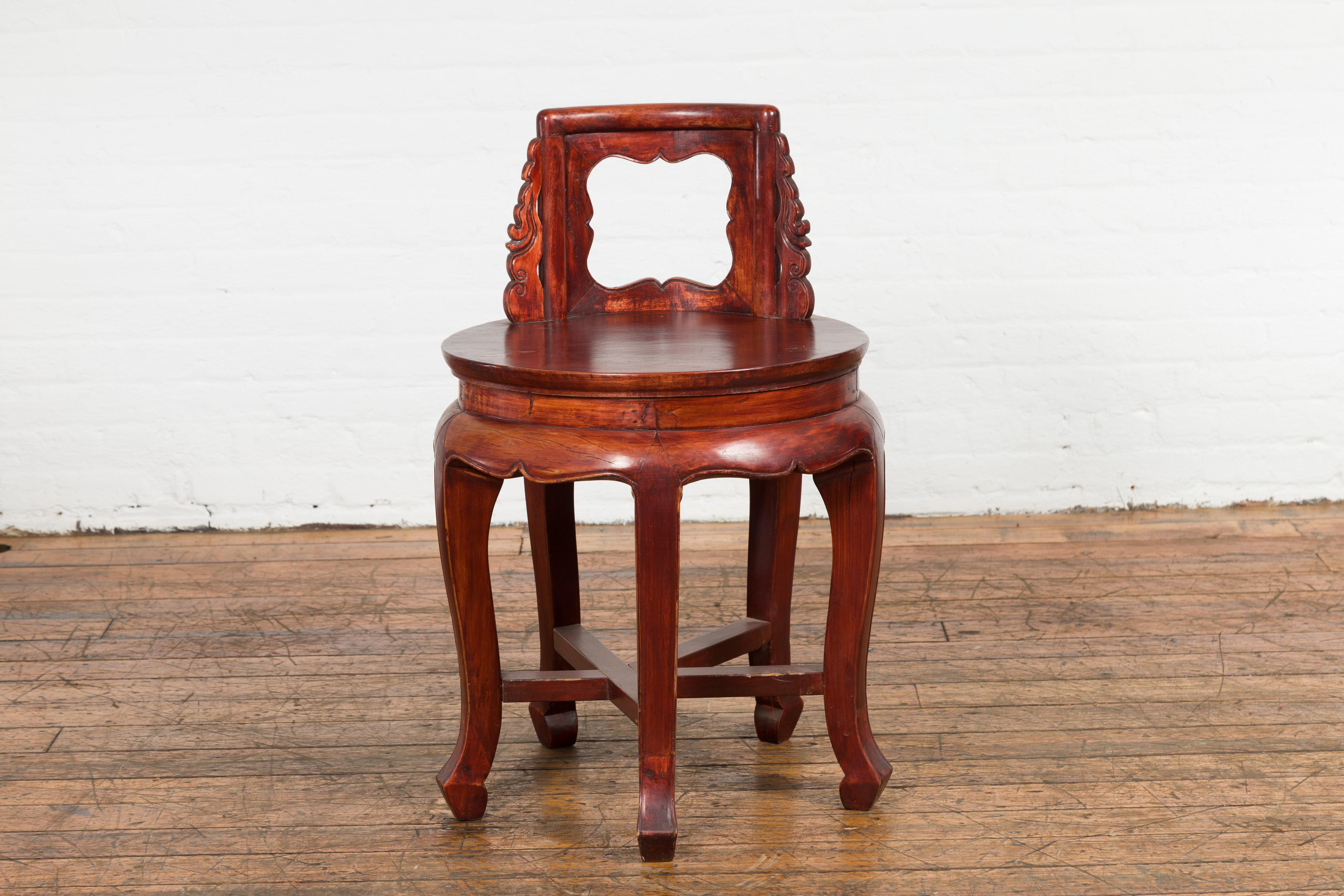 A late Qing Dynasty period unusual diminutive wooden chair from the early 20th century with carved back, curving legs and cross stretcher. This late Qing Dynasty period diminutive wooden chair is a piece of early 20th-century craftsmanship that