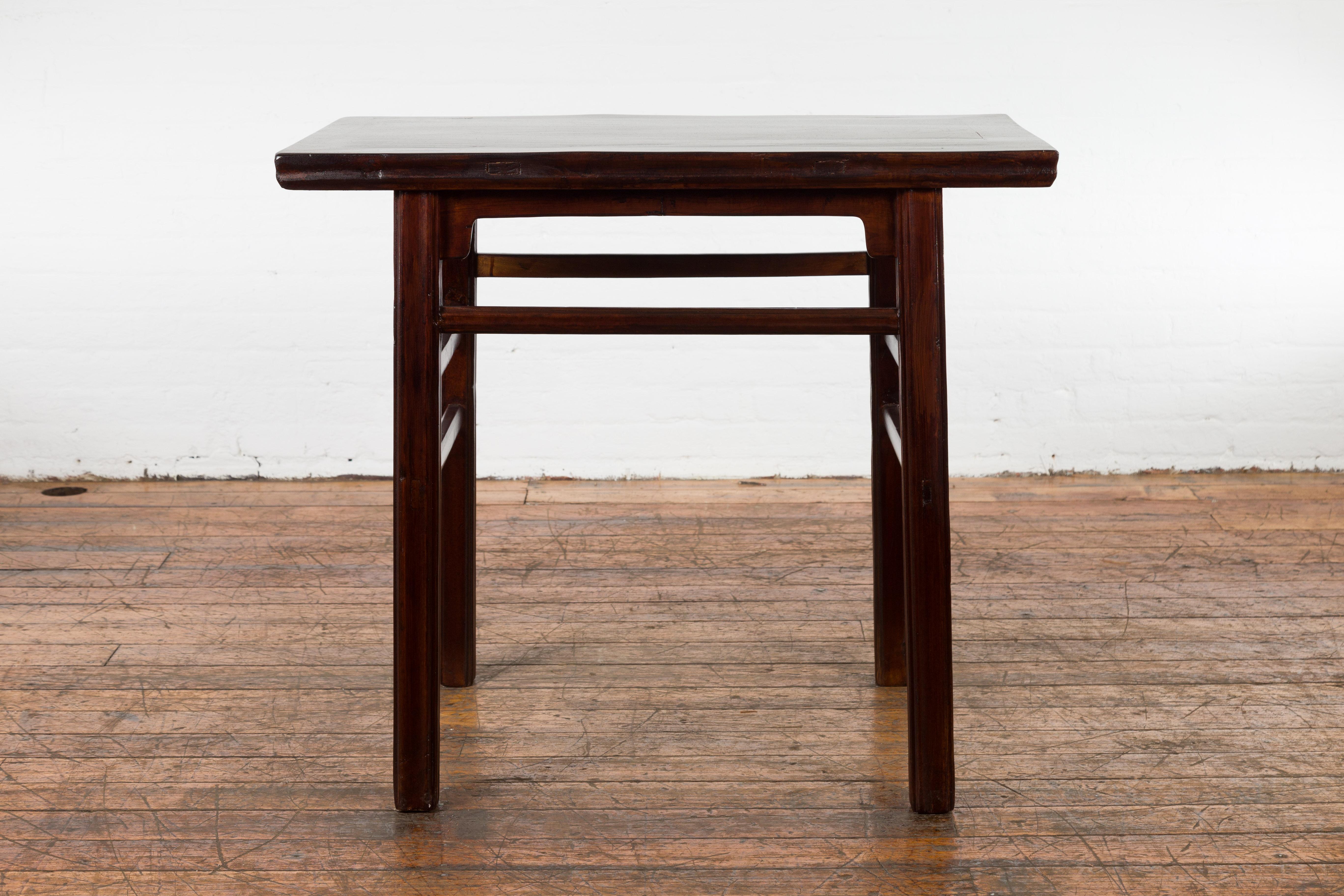A Chinese late Qing Dynasty period elm wood scholar's table from the early 20th century with carved aprons, side stretchers and custom lacquer. Created in China during the late Qing Dynasty period in the early years of the 20th century, this elm