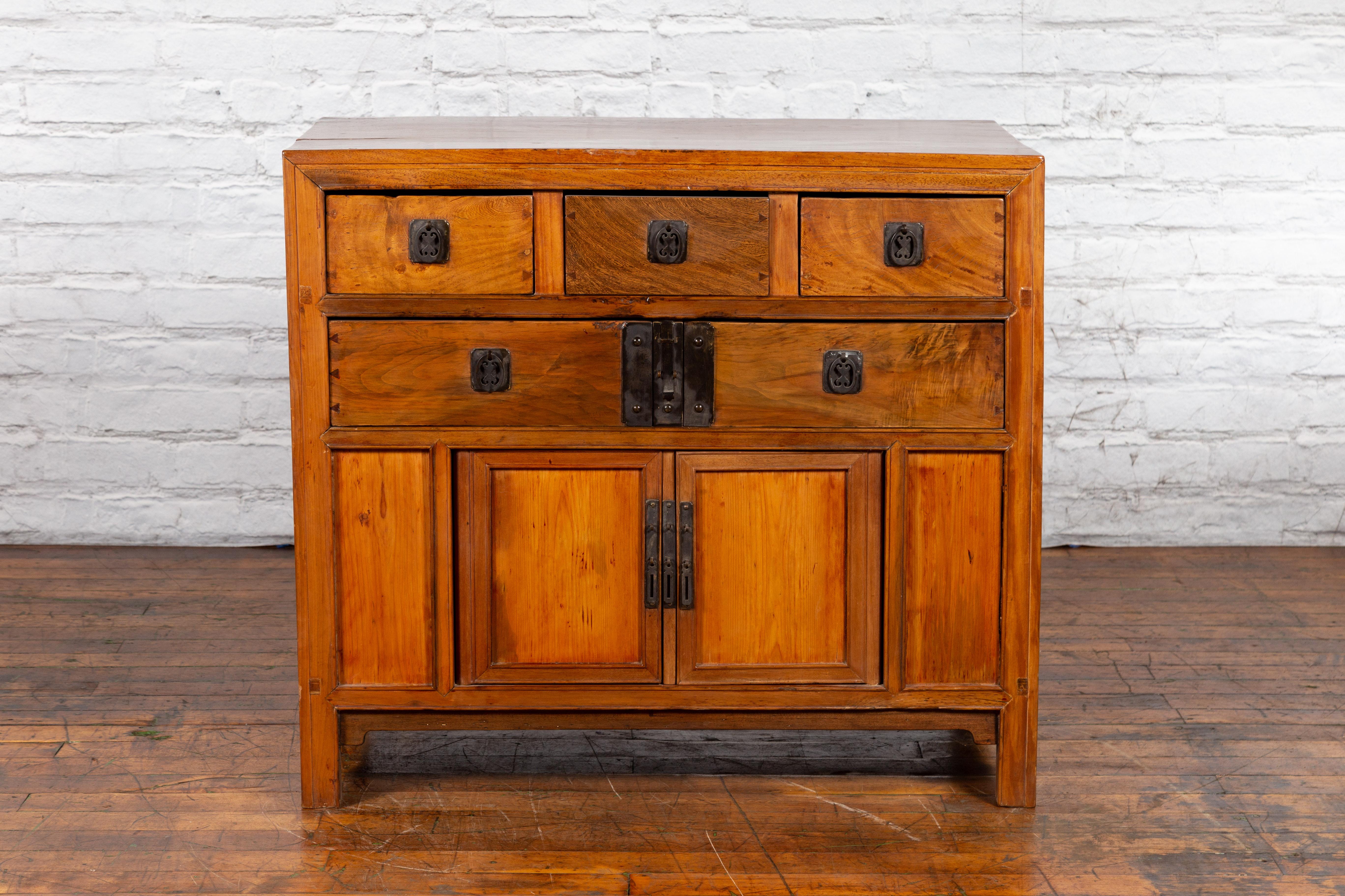 A Chinese Late Qing Dynasty period elmwood cabinet from the early 20th century with five drawers, two doors and iron hardware. Created in China during the late Qing Dynasty in the early years of the 20th century, this elm wood cabinet features a