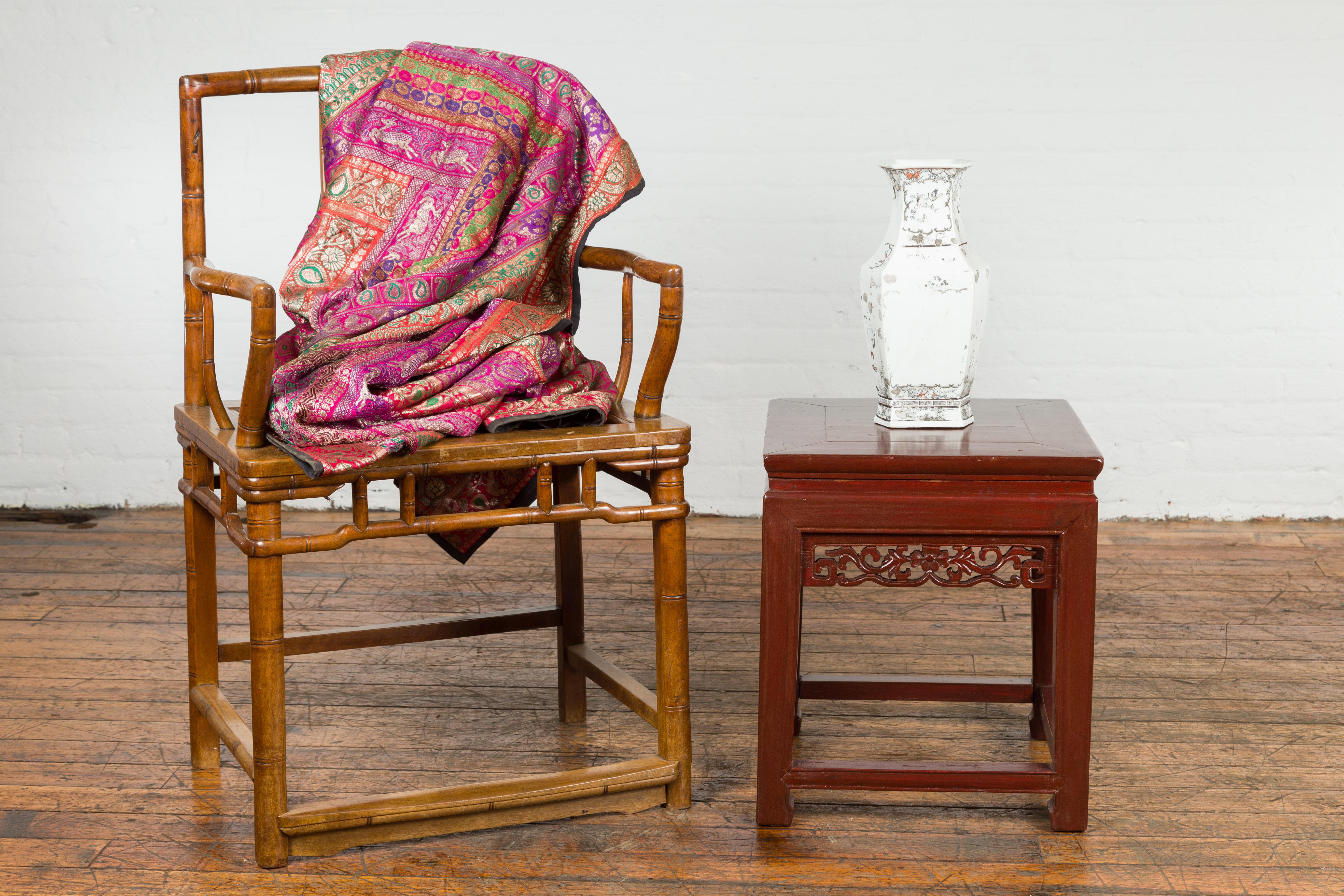A Chinese late Qing Dynasty period small side table or stool from circa 1900 with reddish brown lacquer, waisted apron, carved frieze and horse hoof feet. A charming showcase of late Qing Dynasty craftsmanship, this petite Chinese side table or