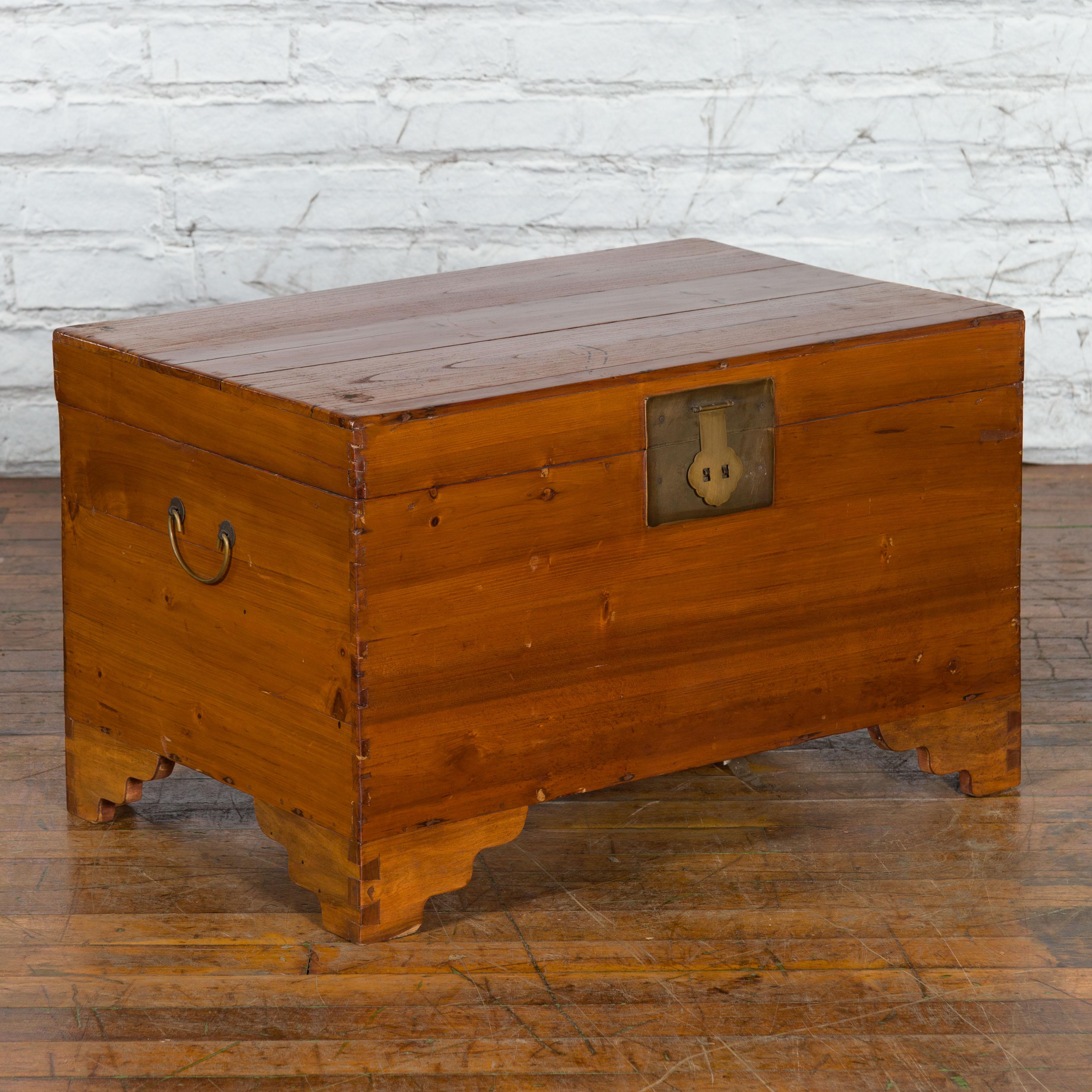 A Chinese late Qing Dynasty period refinished pine chest from the early 20th century, with carved feet and brass hardware. Created in China during the late Qing Dynasty period in the early years of the 20th century, this versatile piece would be