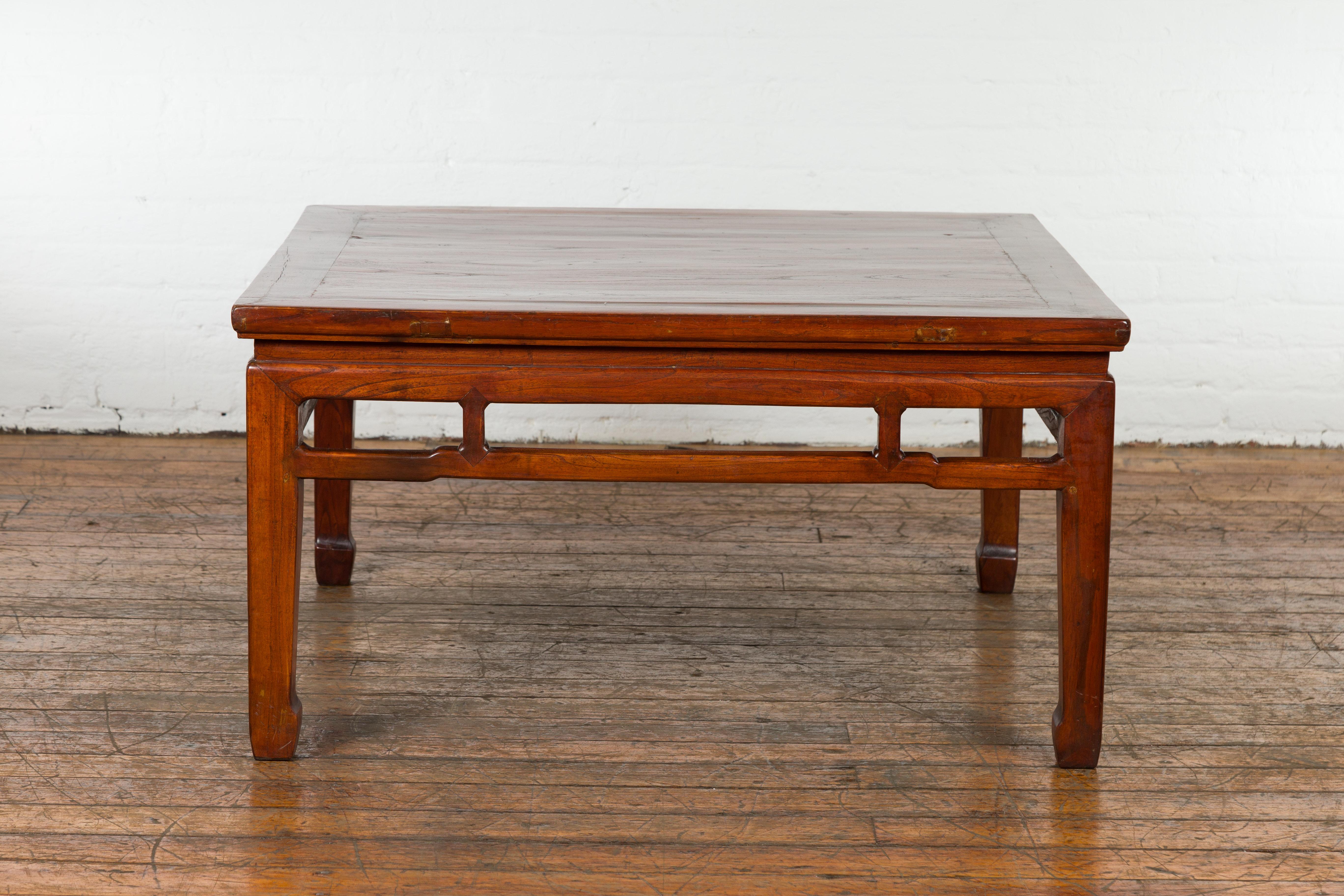 A Chinese late Qing Dynasty period square top coffee table from the early 20th century with pierced apron, pillar strut motifs, humpback stretchers on all sides and horsehoof extremities. Emanating the spirit of the early 20th-century late Qing